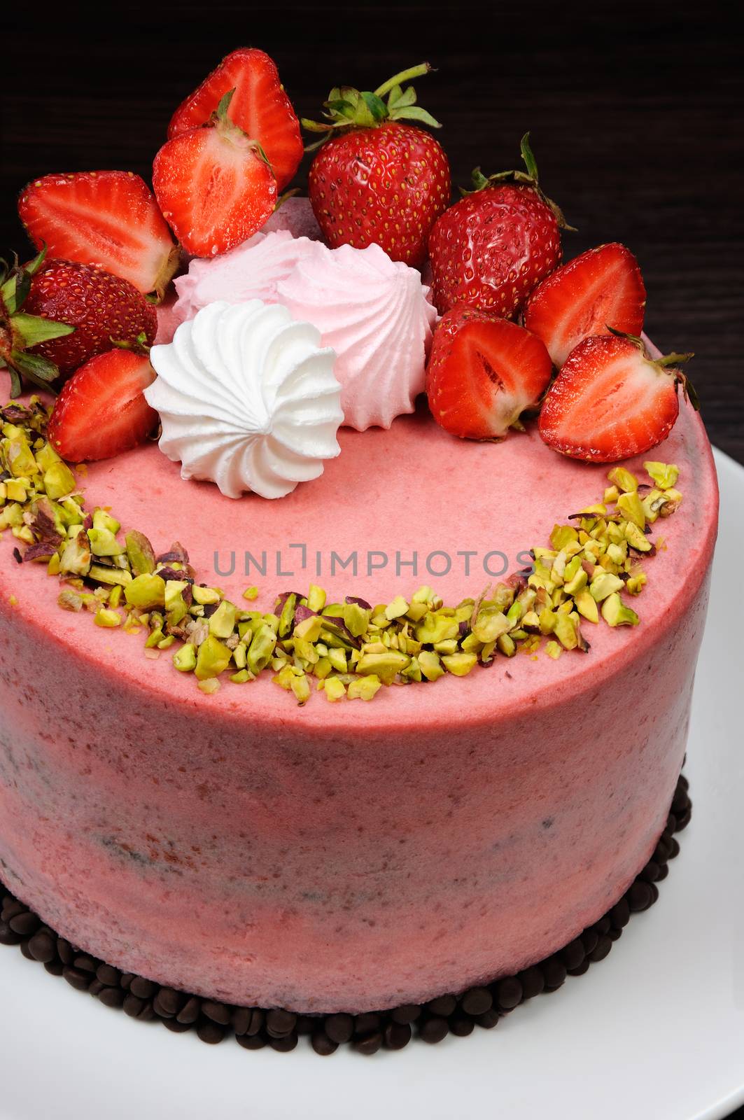 Chocolate strawberry cake decorated with berries, meringue and pistachios