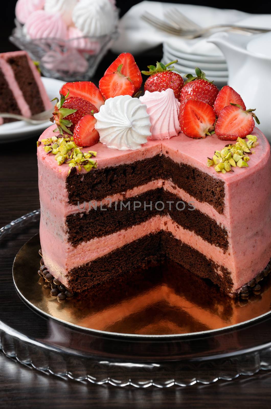 Chocolate strawberry cake decorated with berries, meringue and pistachios in a cut
