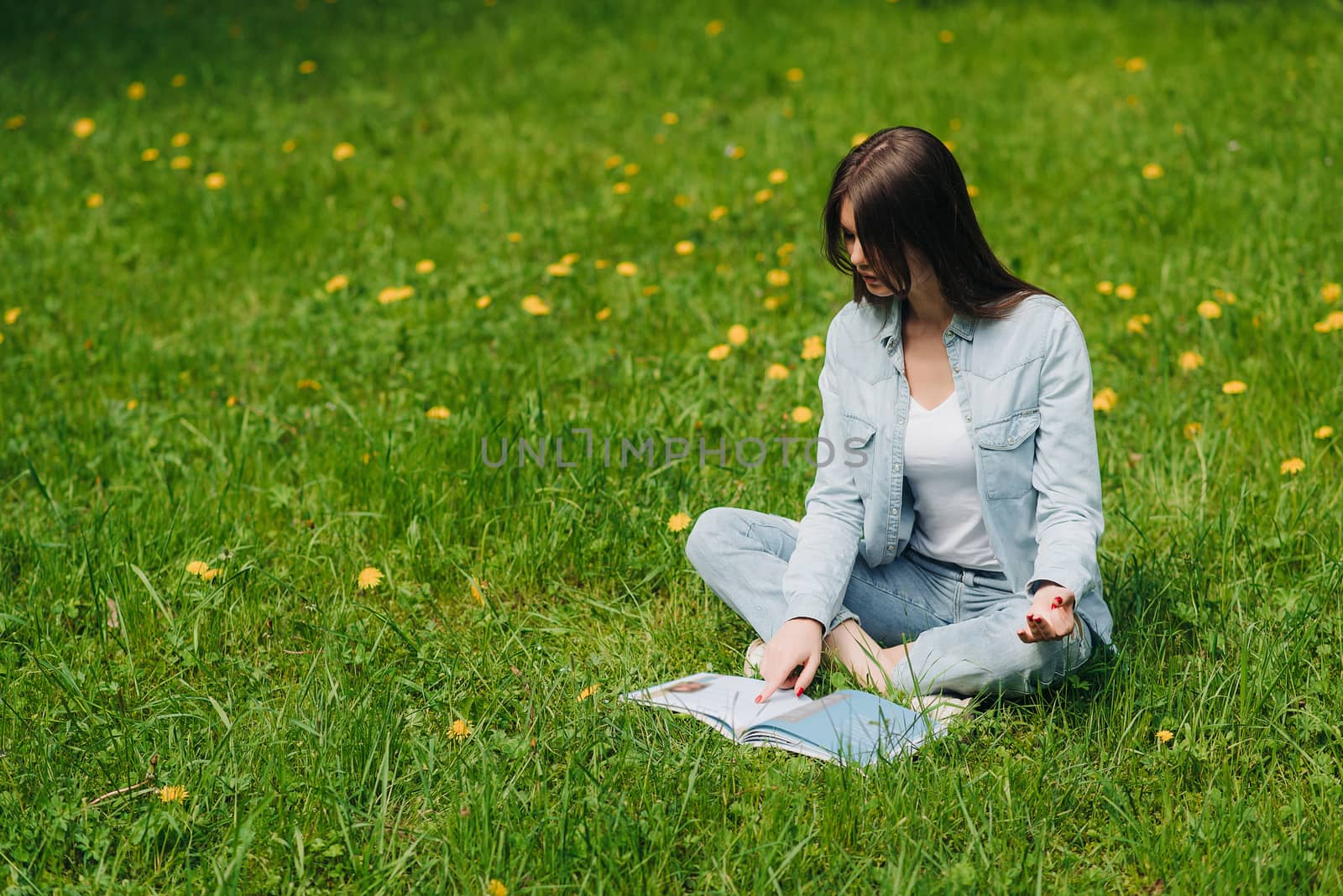 Woman reading on grass in park by ALotOfPeople