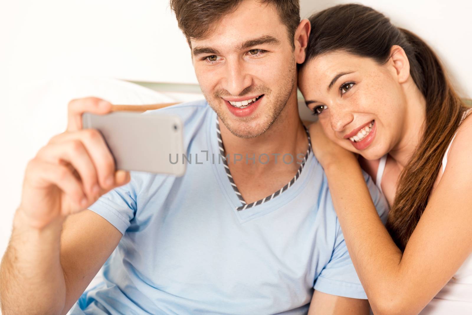 Young couple on bed watching videos on a cellphone
