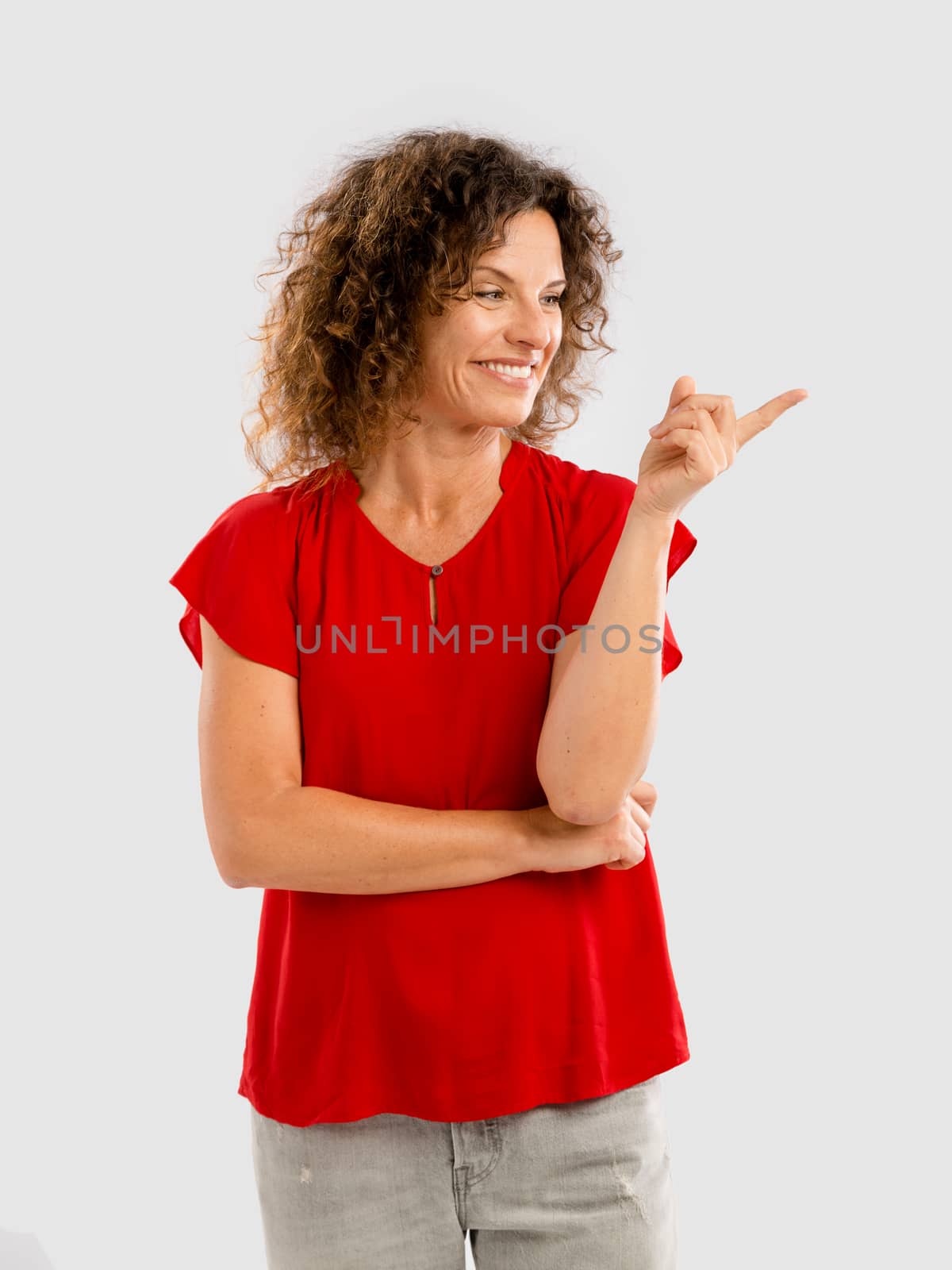 Portrait of a smiling middle aged brunette pointing with her left arm