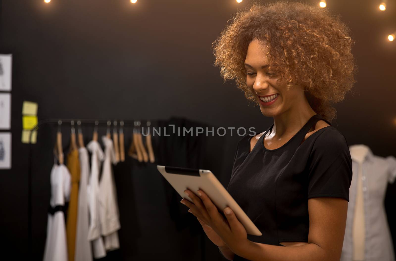 A young fashion designer on her atelier working with a tablet