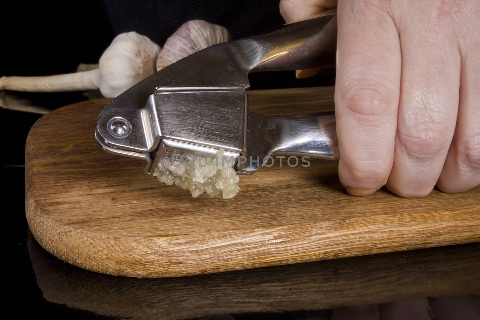 Garlic press and cloves of garlic laid on a wooden table background