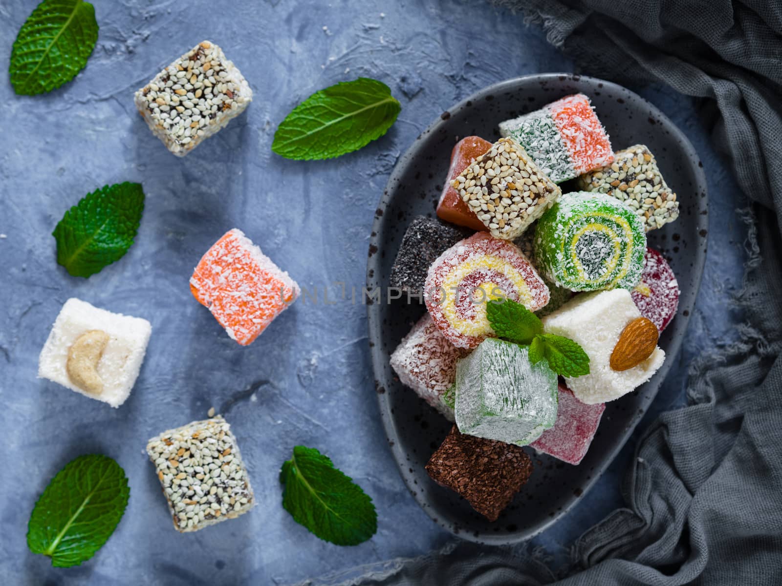 Turkish delight on blue concrete background. Assortment of traditional easten sweet dessert in trandy blue plate. Selective focus. Top view or flat lay