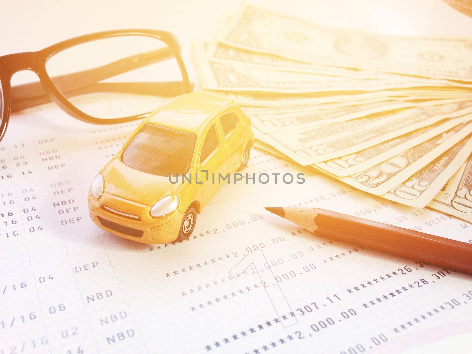 Business, finance, savings, banking or car loan concept : Miniature car model, pencil, eyeglasses, money and savings account passbook or financial statement on white background