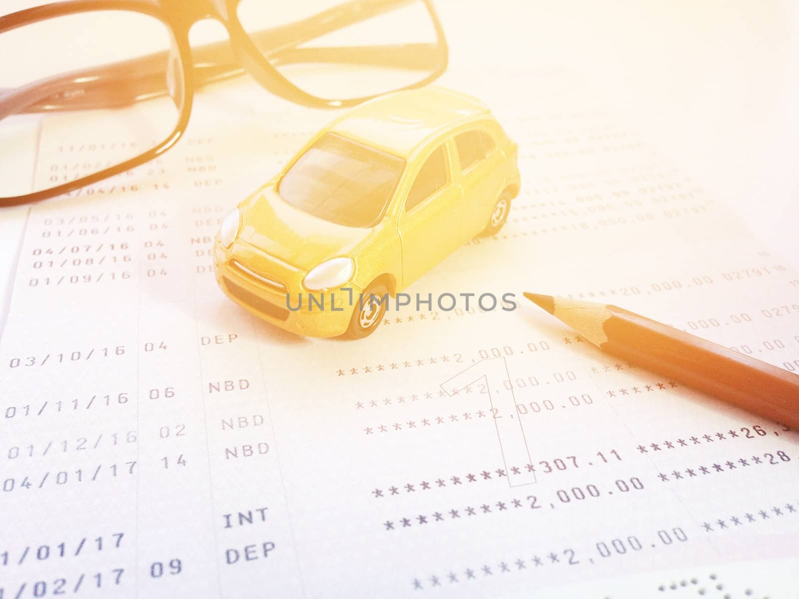 Business, finance, savings, banking or car loan concept : Miniature car model, pencil, eyeglasses and savings account passbook or financial statement on white background