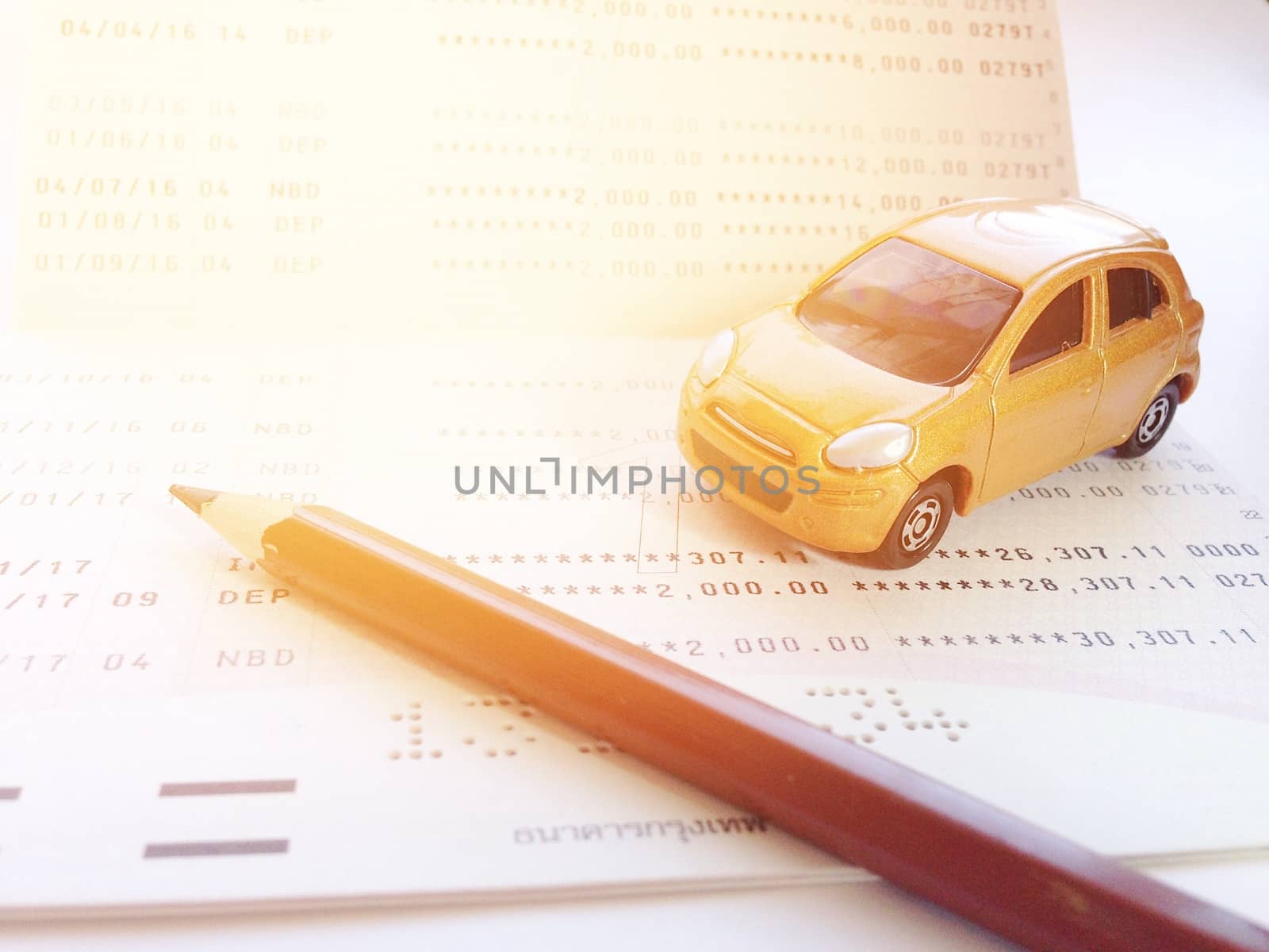 Business, finance, savings, banking or car loan concept : Miniature car model, pencil and savings account passbook or financial statement on white background