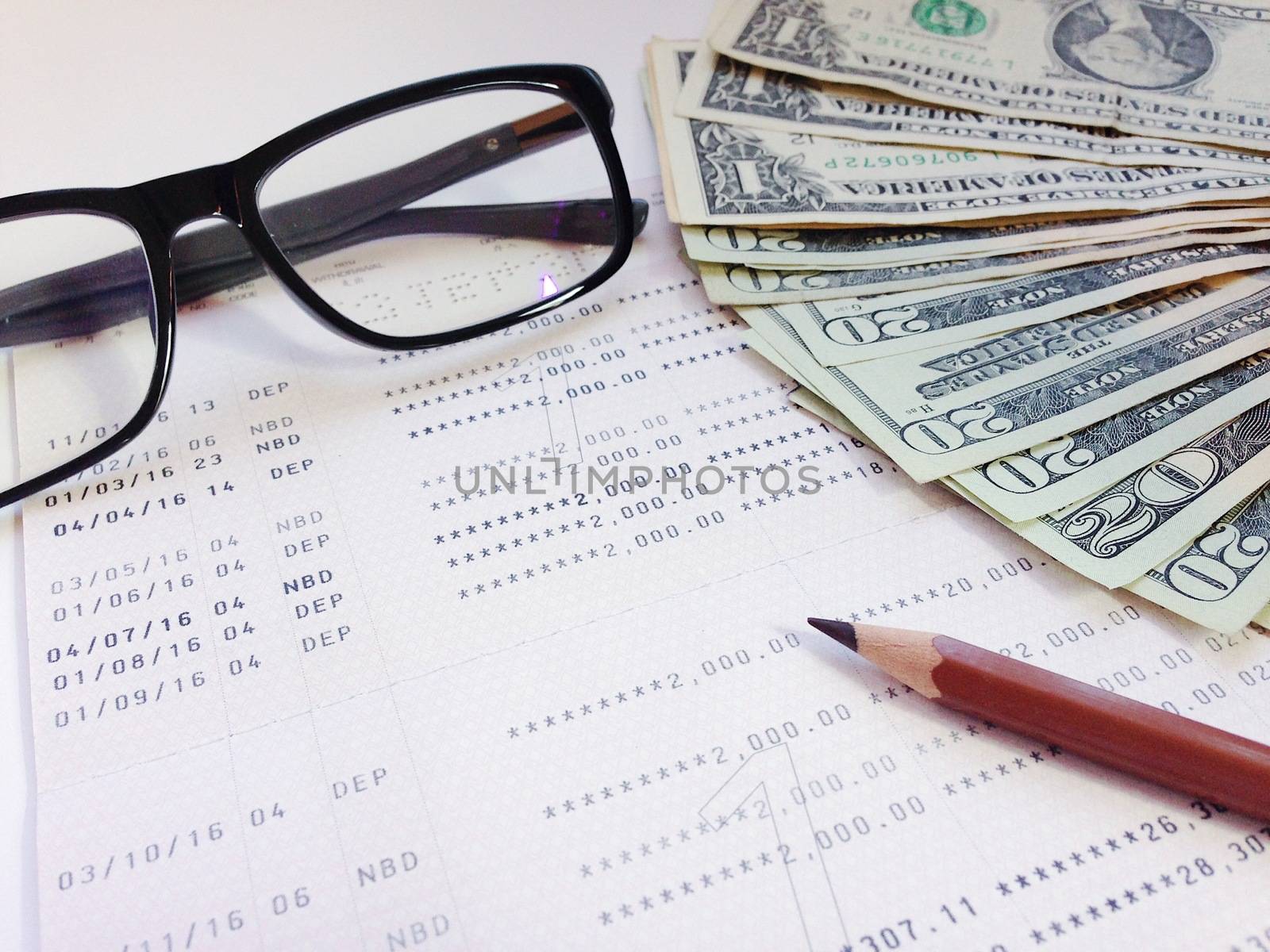 Business, finance, savings, banking or  loan concept : Pencil, eyeglasses, money and savings account passbook or financial statement on white background