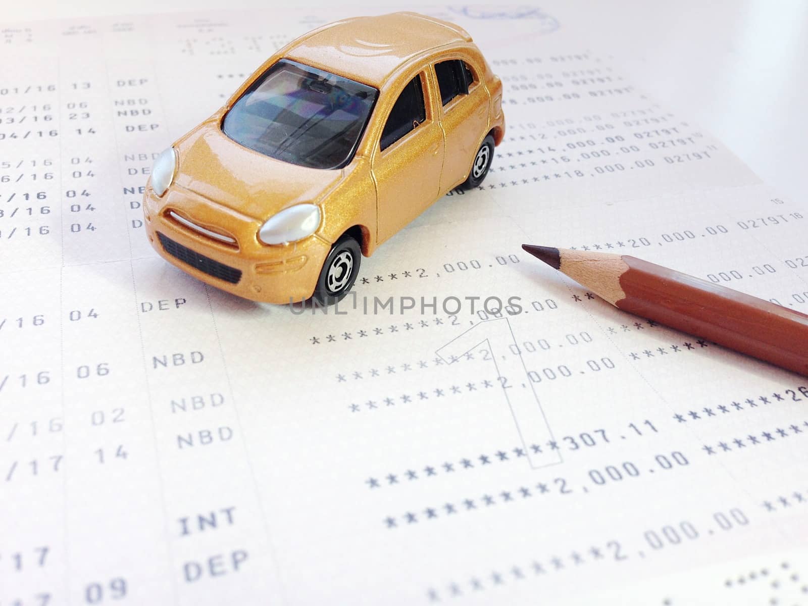 Business, finance, savings, banking or car loan concept : Miniature car model, pencil and savings account passbook or financial statement on white background