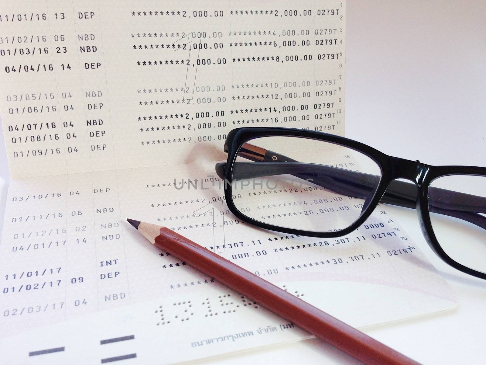 Business, finance, savings, banking or  loan concept : Pencil, eyeglasses and savings account passbook or financial statement on white background