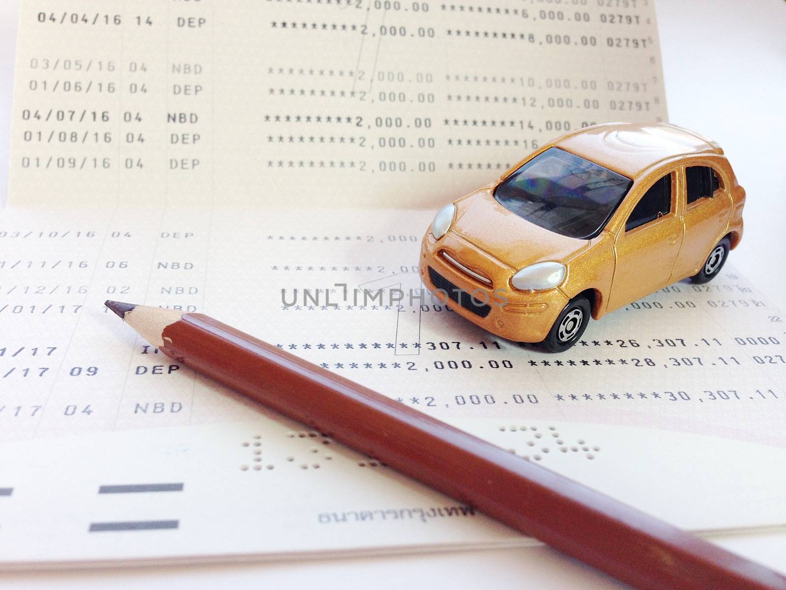Business, finance, savings, banking or car loan concept : Miniature car model, pencil and savings account passbook or financial statement on white background