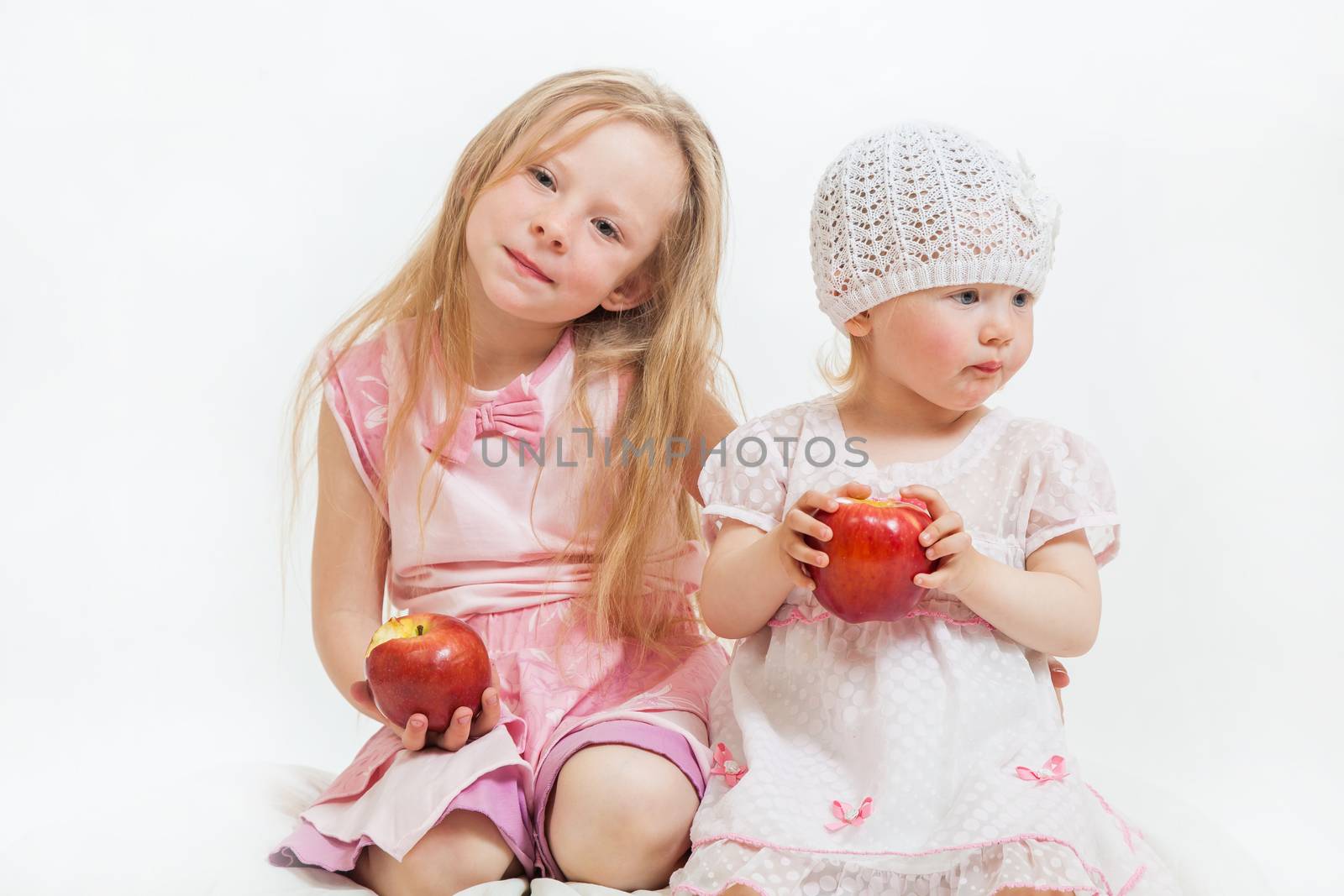 two little girls sit on the isolated background