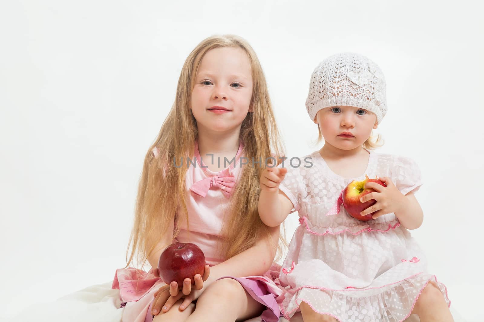 two little girls sit on the isolated background