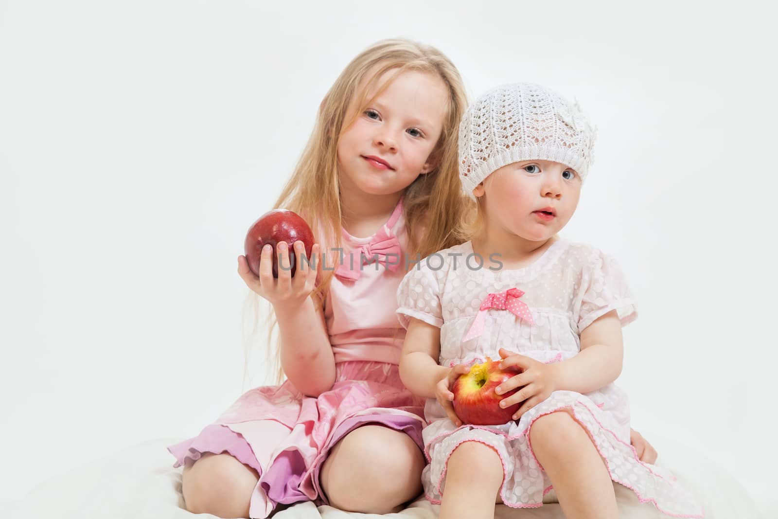 two little girls sit on the isolated background