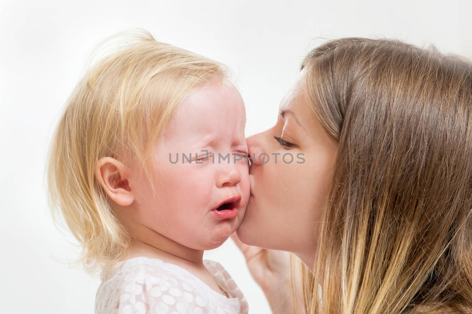 mother kisses the crying girl on the isolated background