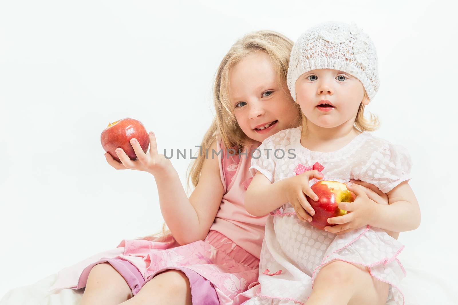 two little girls sit on the isolated background