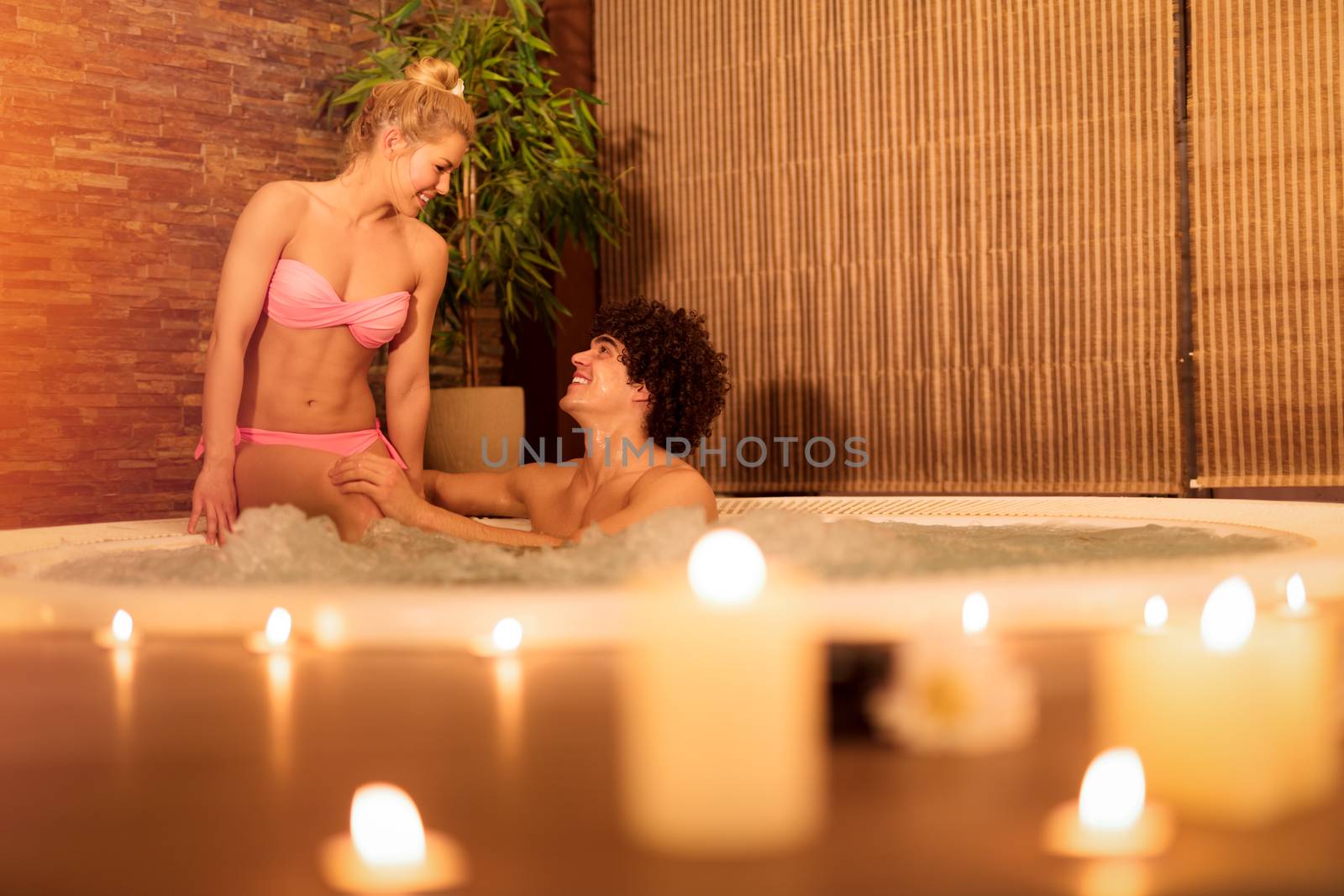 Beautiful young couple enjoying in a hot tub at the spa centre.