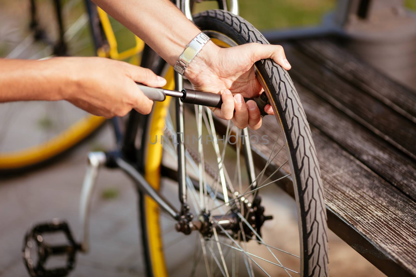 Close-up of a man pumping bicycle wheel on the street.
