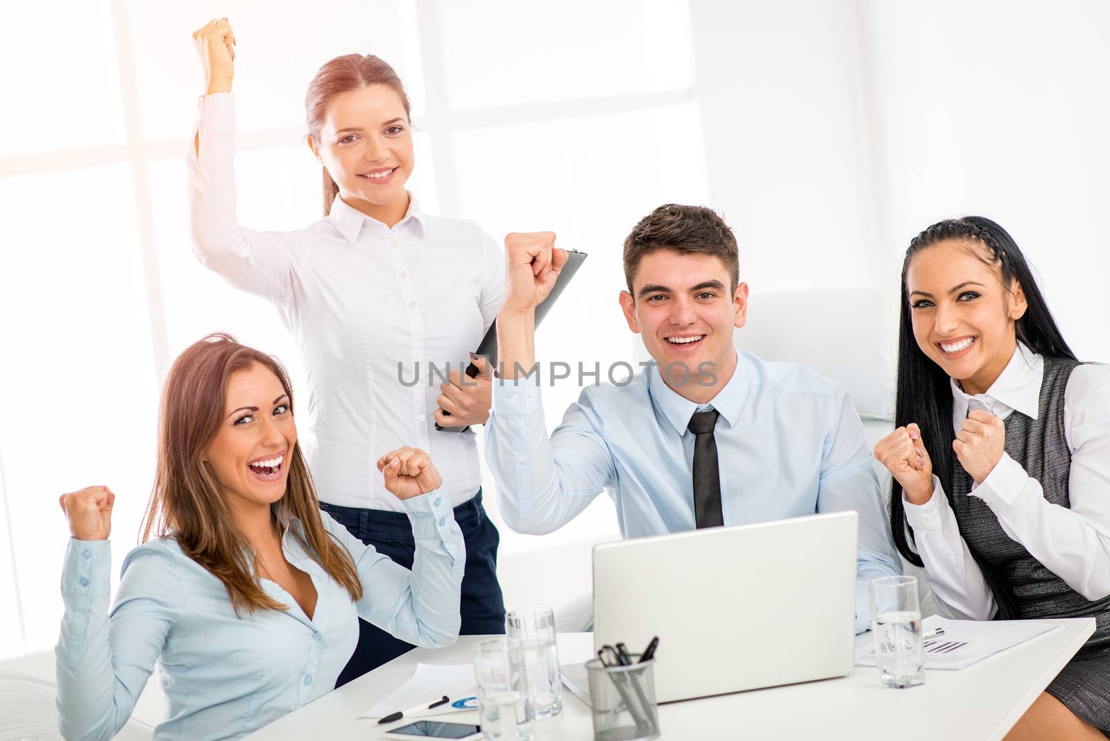 Successful young smiling colleagues working at laptop in the office.