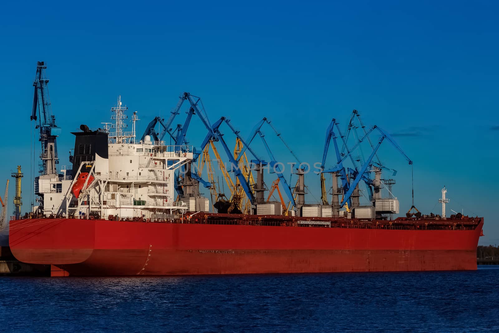 Red cargo ship loading in the port of Riga, Europe