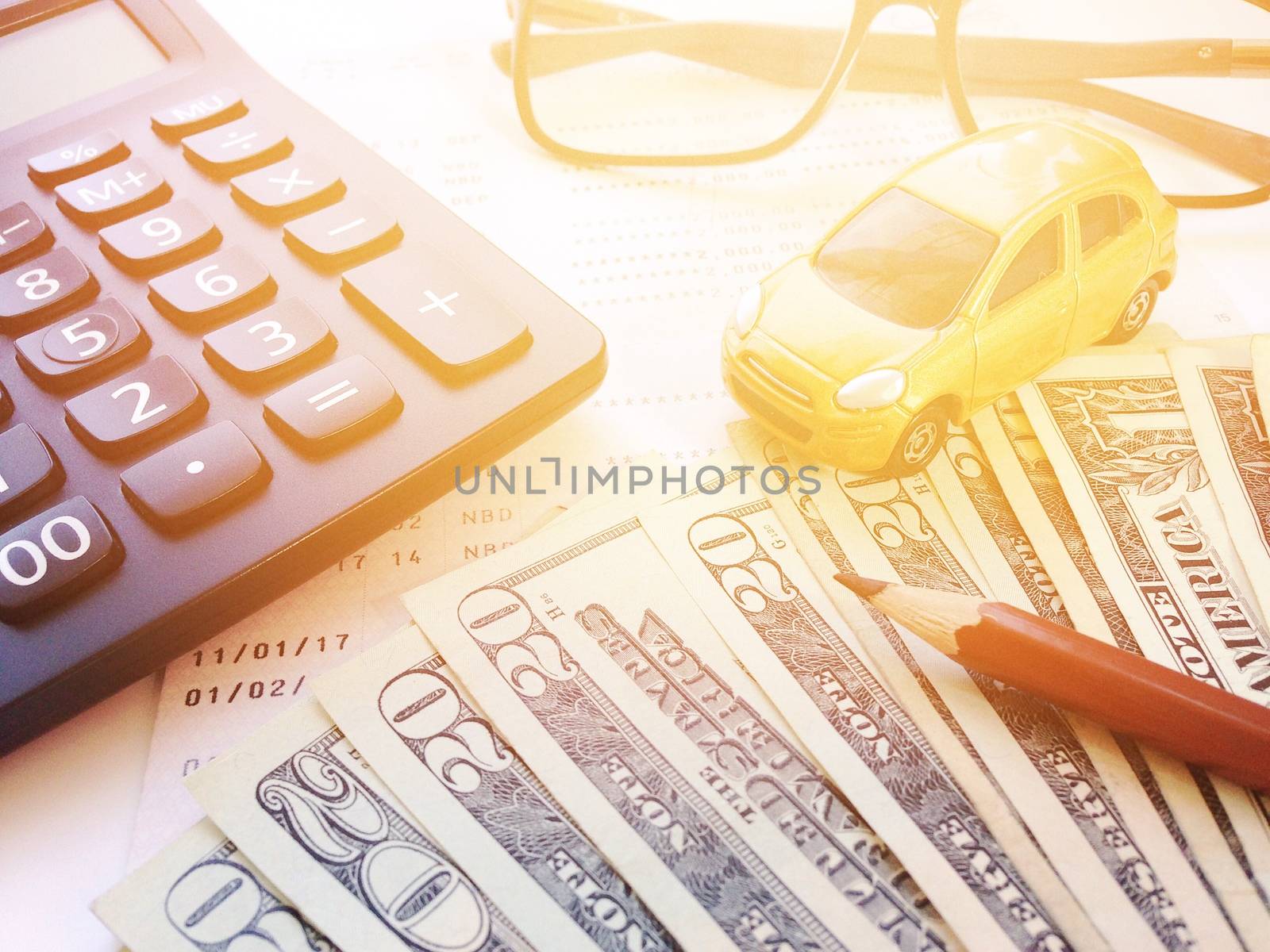 Business, finance, savings, banking or car loan concept : Miniature car model, pencil, calculator, eyeglasses, money and savings account passbook or financial statement on white background