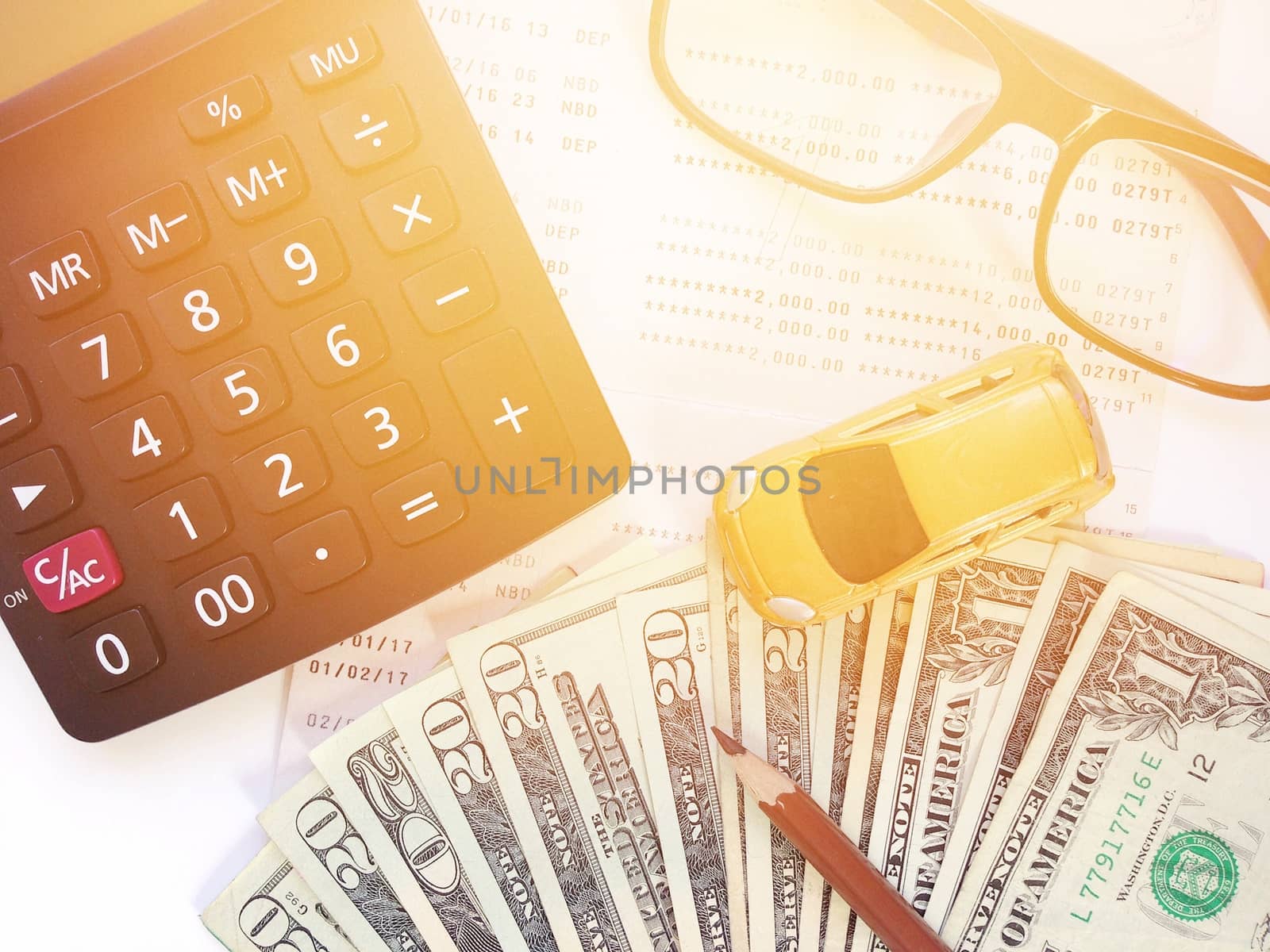 Business, finance, savings, banking or car loan concept : Miniature car model, pencil, money, calculator, eyeglasses and savings account passbook or financial statement on white background