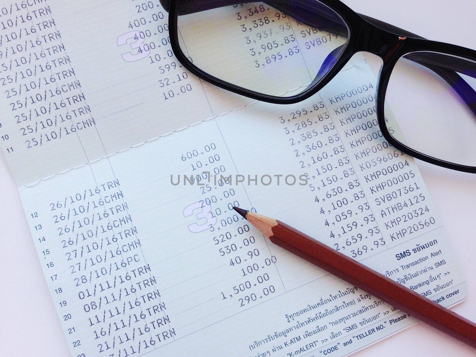 Business, finance, savings, banking or  loan concept : Pencil, eyeglasses and savings account passbook or financial statement on white background