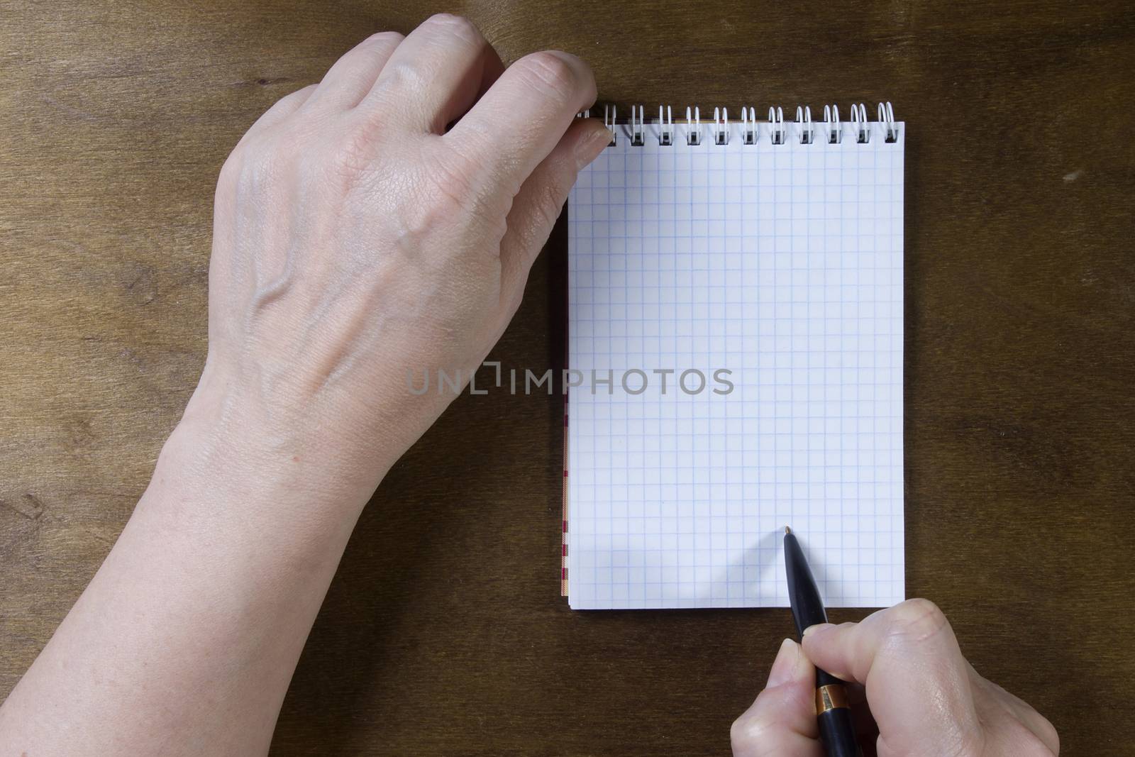 Hand writing on empty notepad on a wooden table