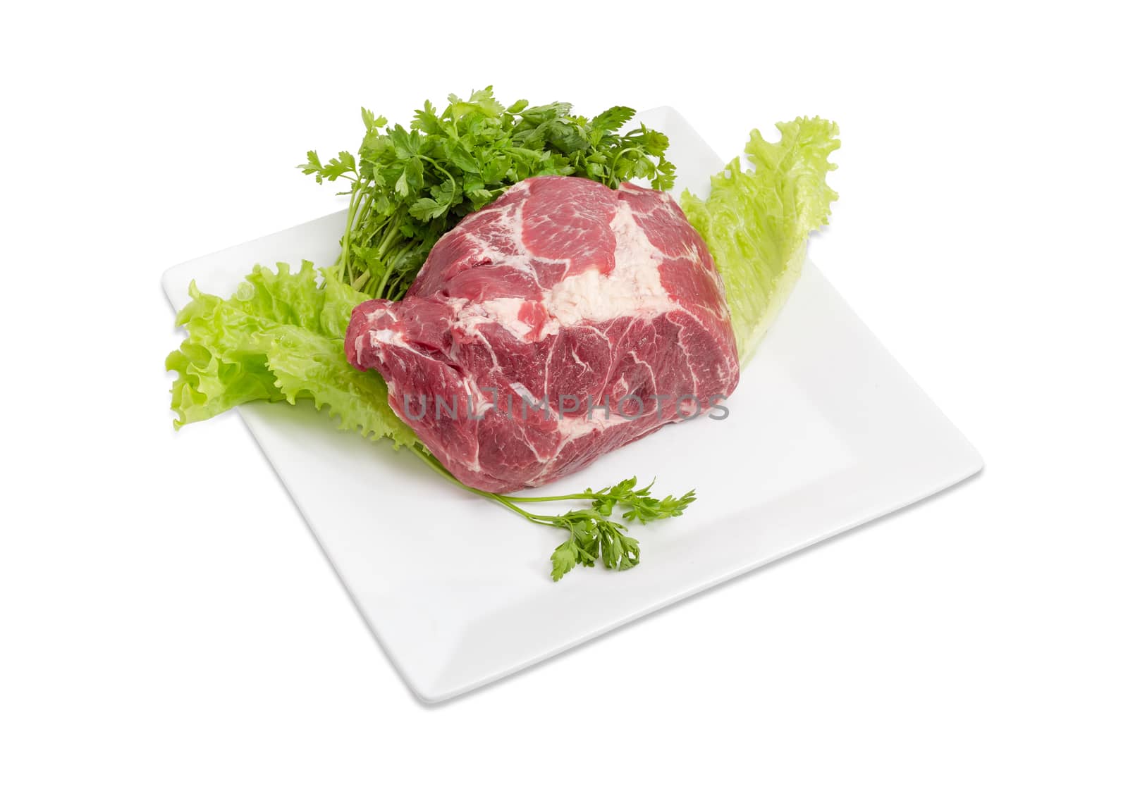 Piece of a fresh uncooked pork neck on the lettuce leaves and bundle of the parsley on the white square dish on a light background
