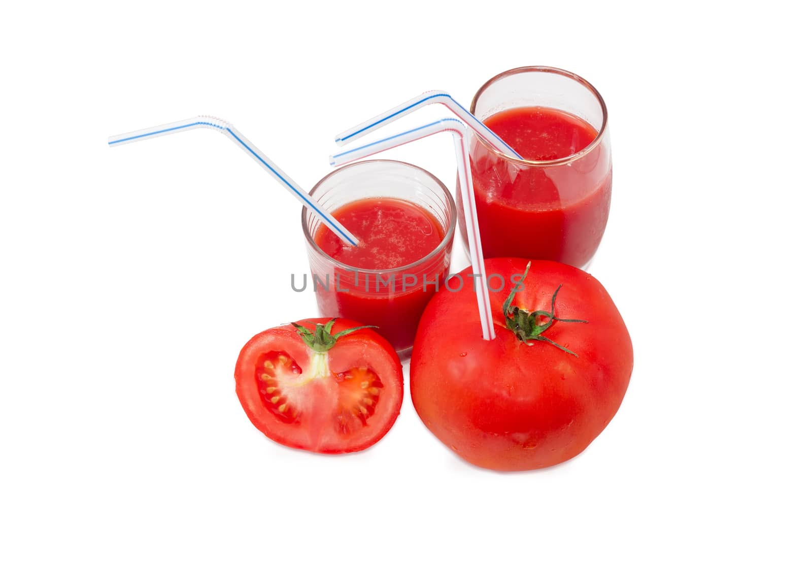 Big fresh whole tomato with bendable drinking straw inserted into it, half of the tomato and two different glasses with tomato juice and drinking straws on a light background
