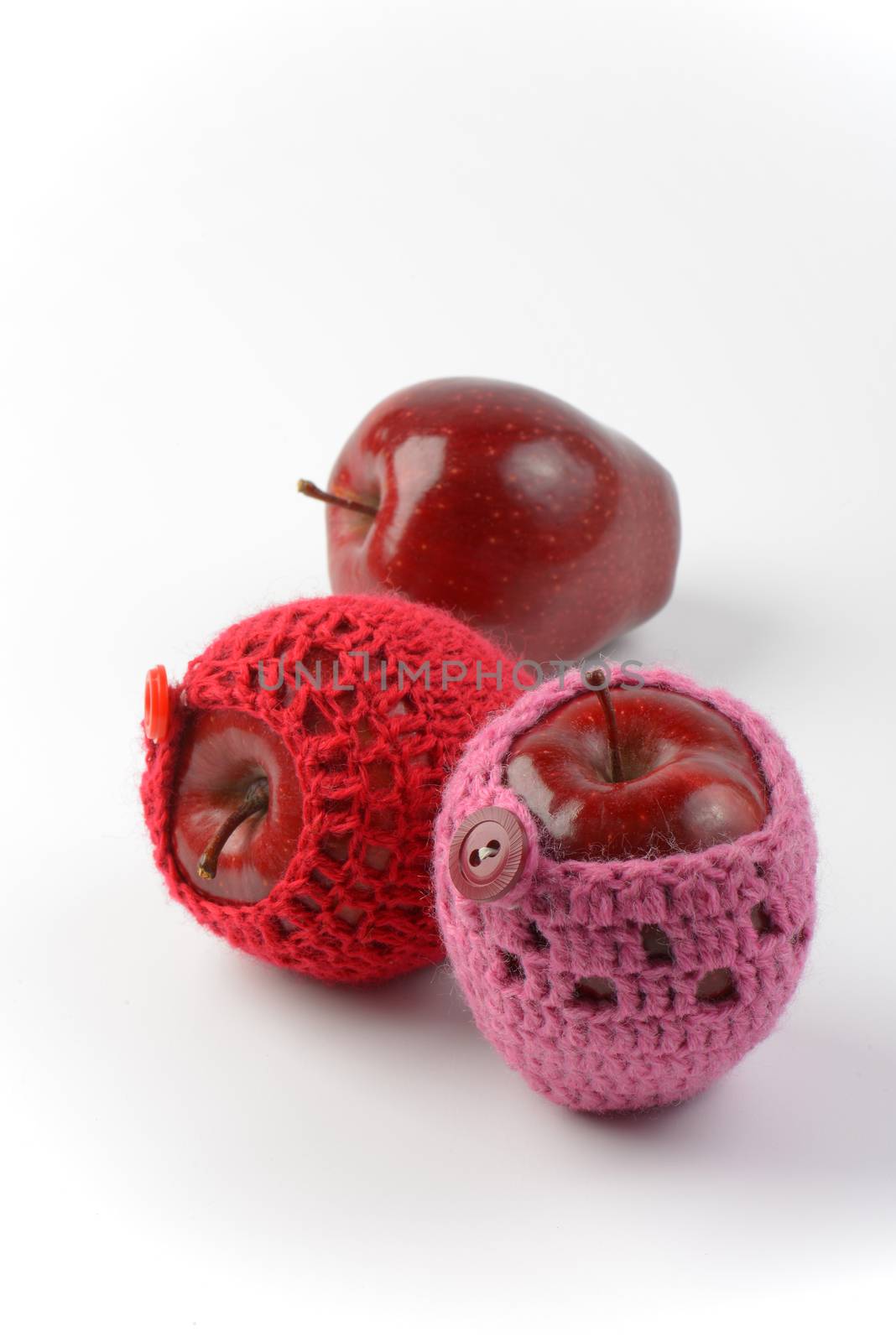 three red apples, two of them in crochet cozies