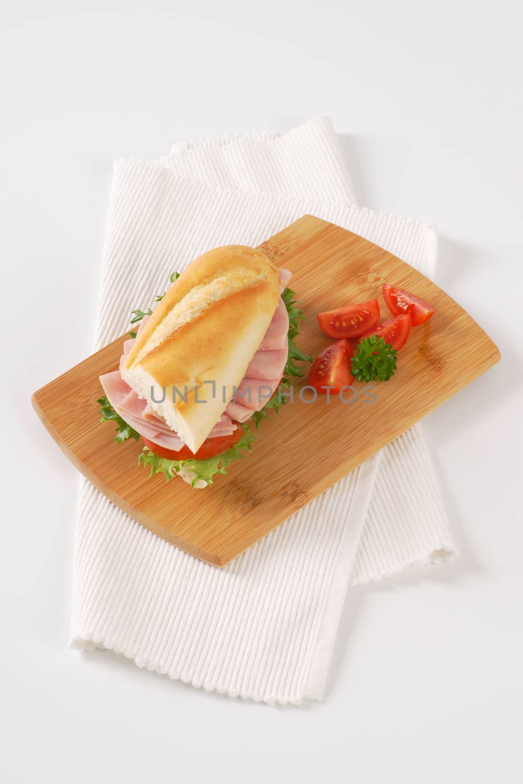 French bread sandwich with ham on wooden cutting board