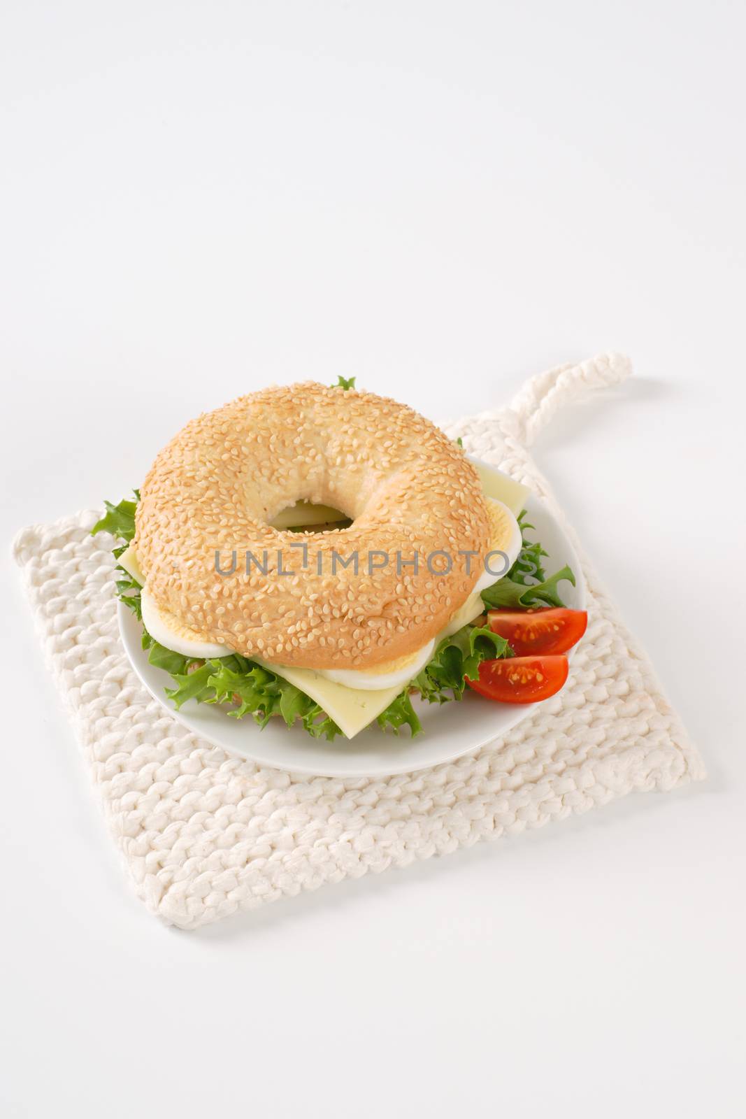 bagel sandwich with eggs and cheese on white plate