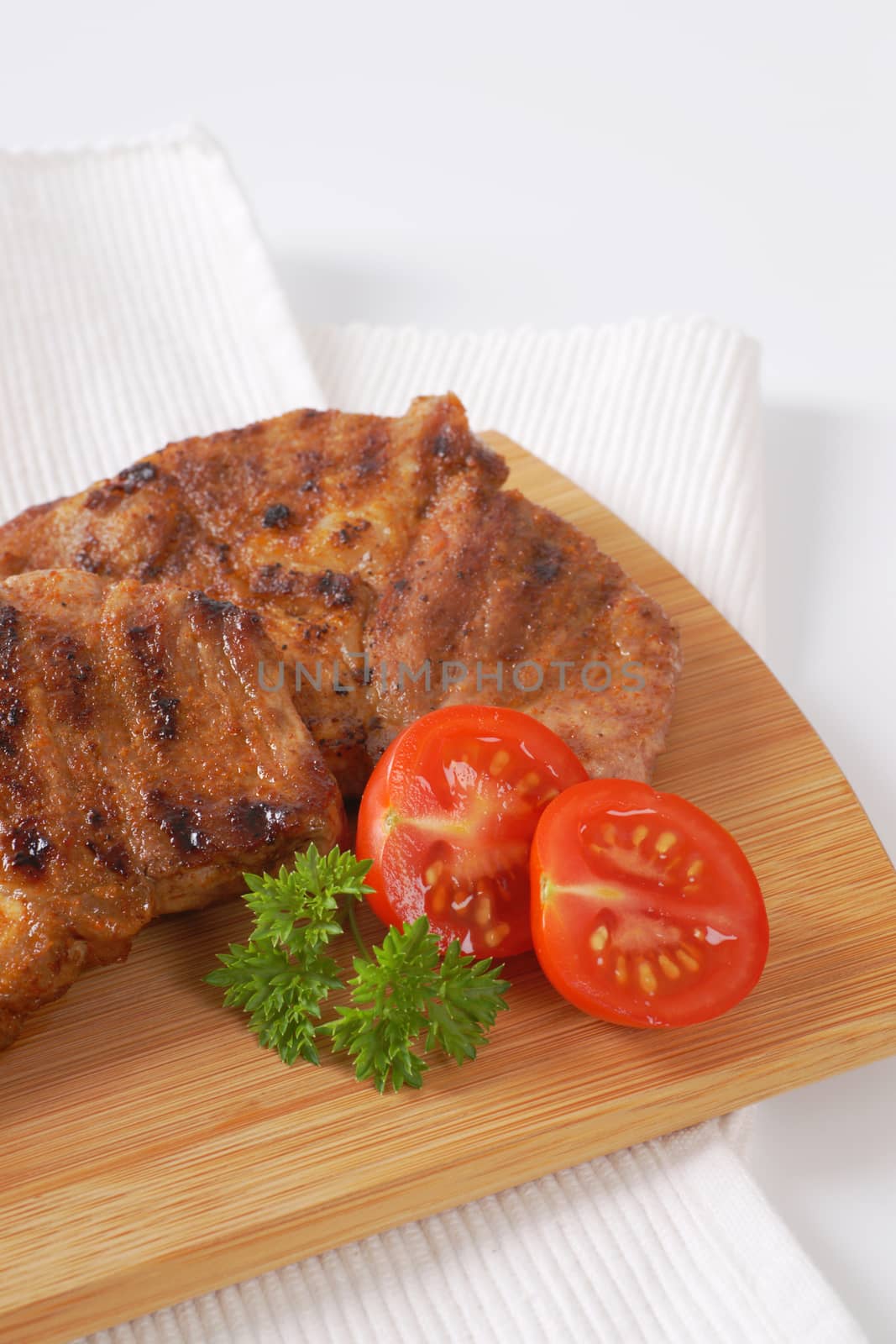 two slices of grilled pork meat on wooden cutting board