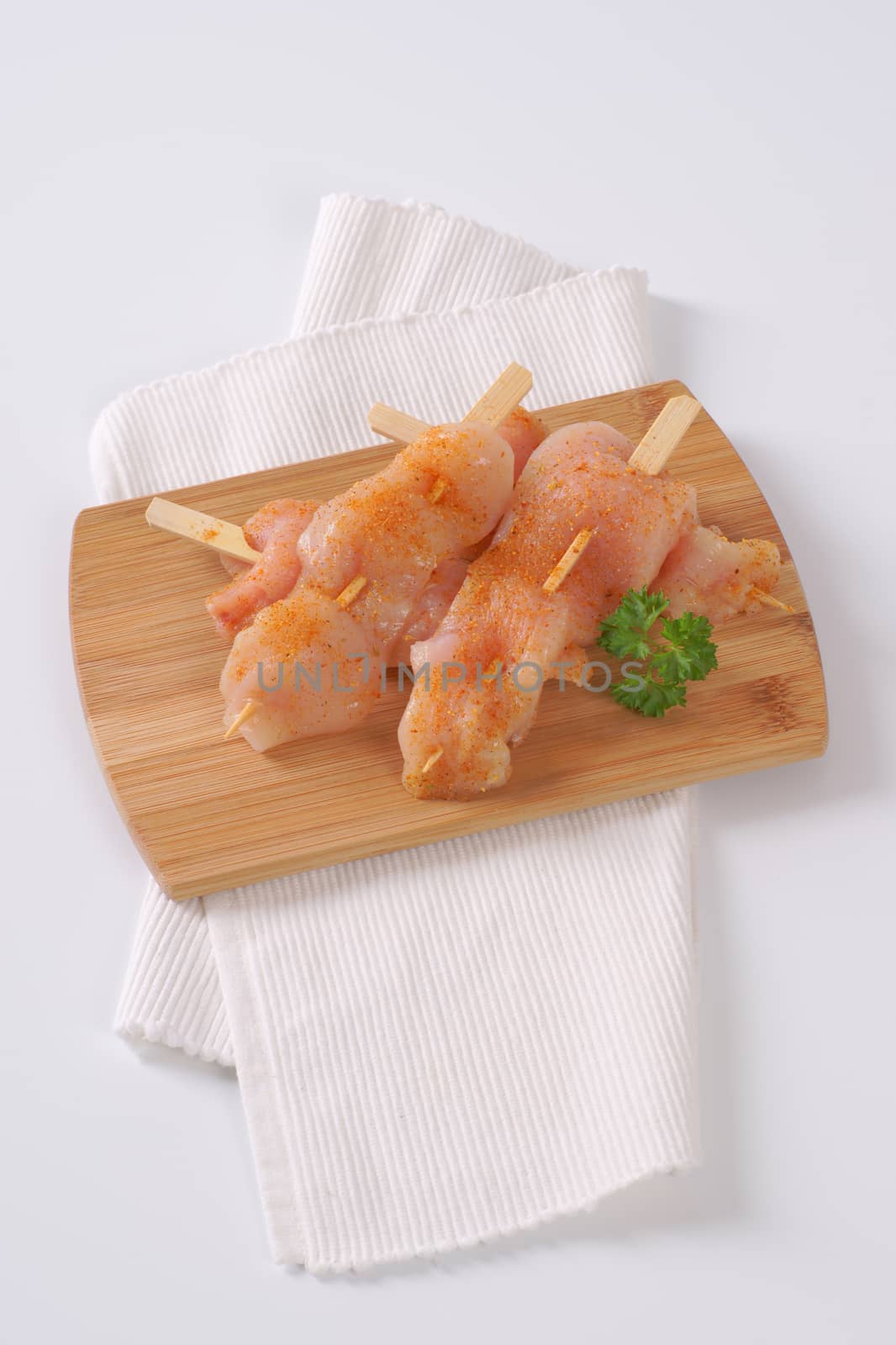 raw chicken skewers on wooden cutting board