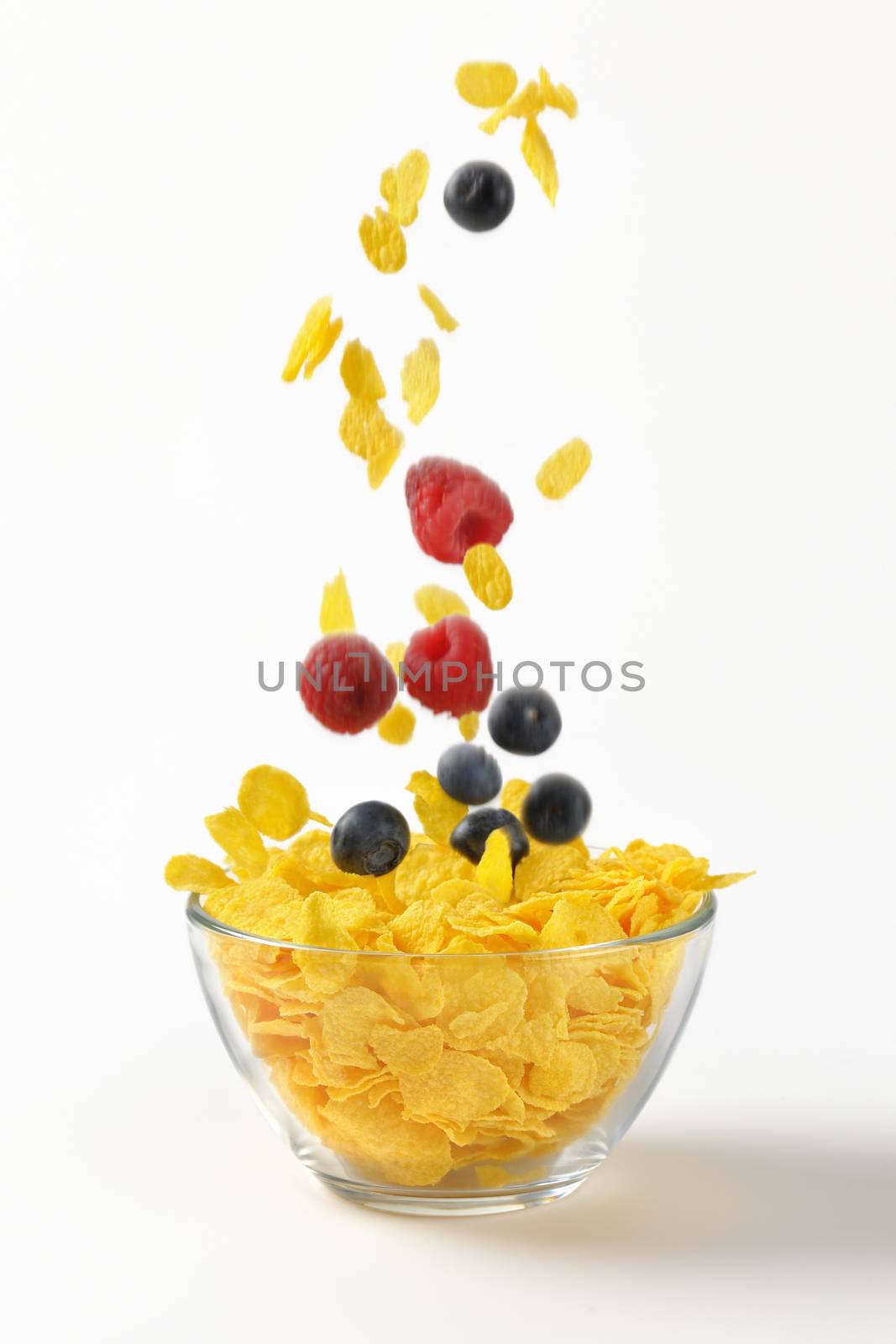 berry fruit falling into bowl of corn flakes on white background