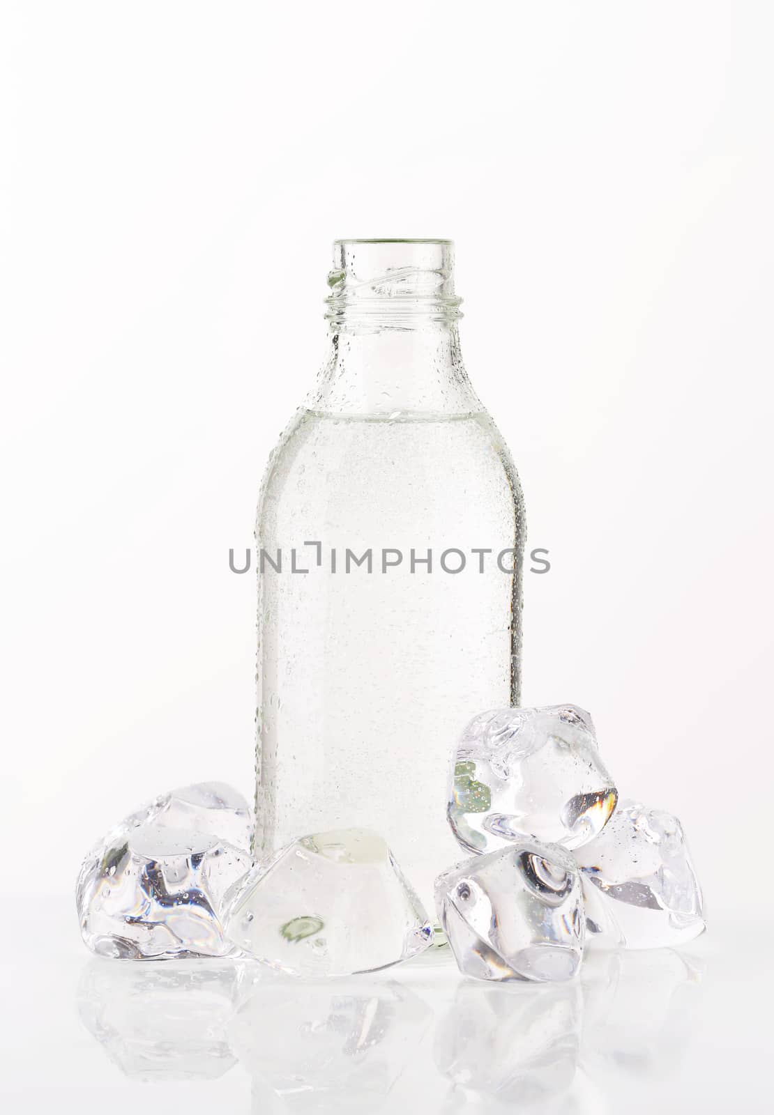 bottle of fresh water and ice cubes on white background