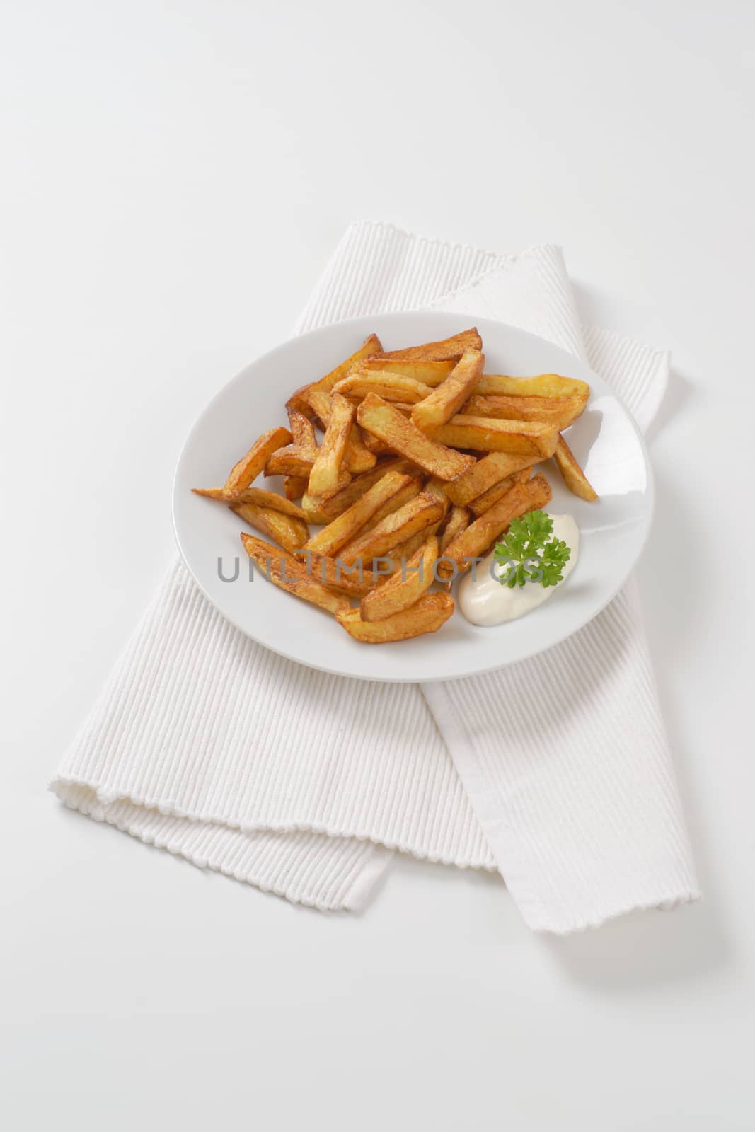 plate of chipped potatoes with mayonnaise on white place mat