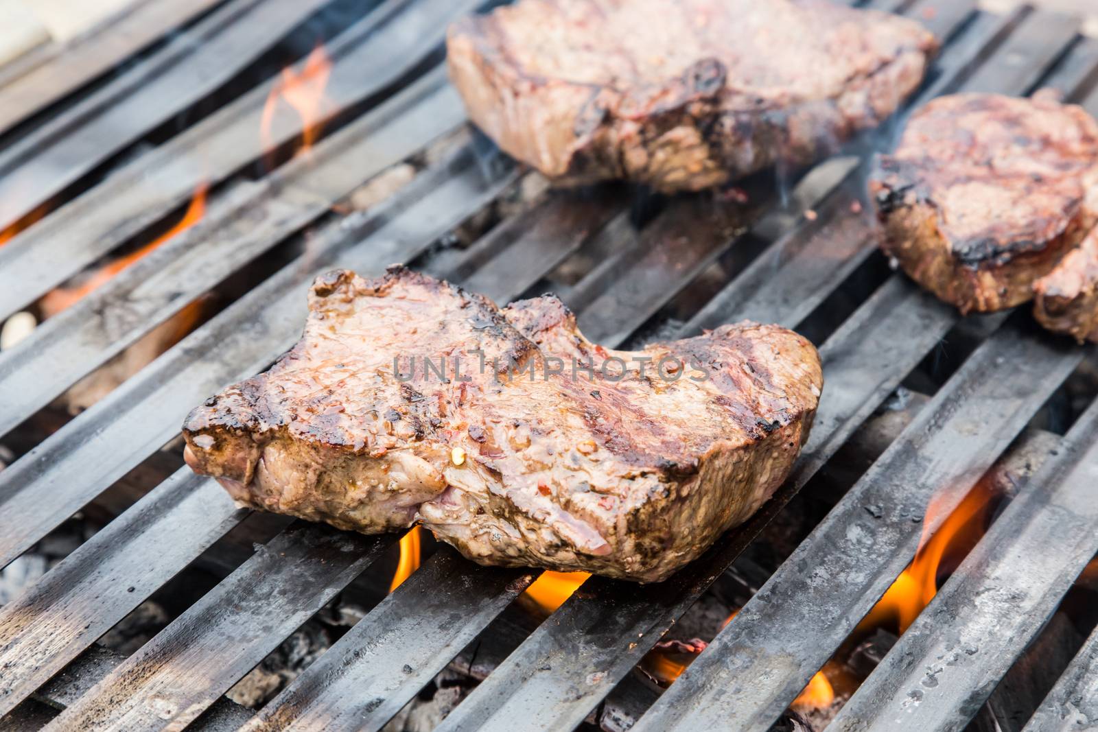 Beef steaks on the grill with flames.