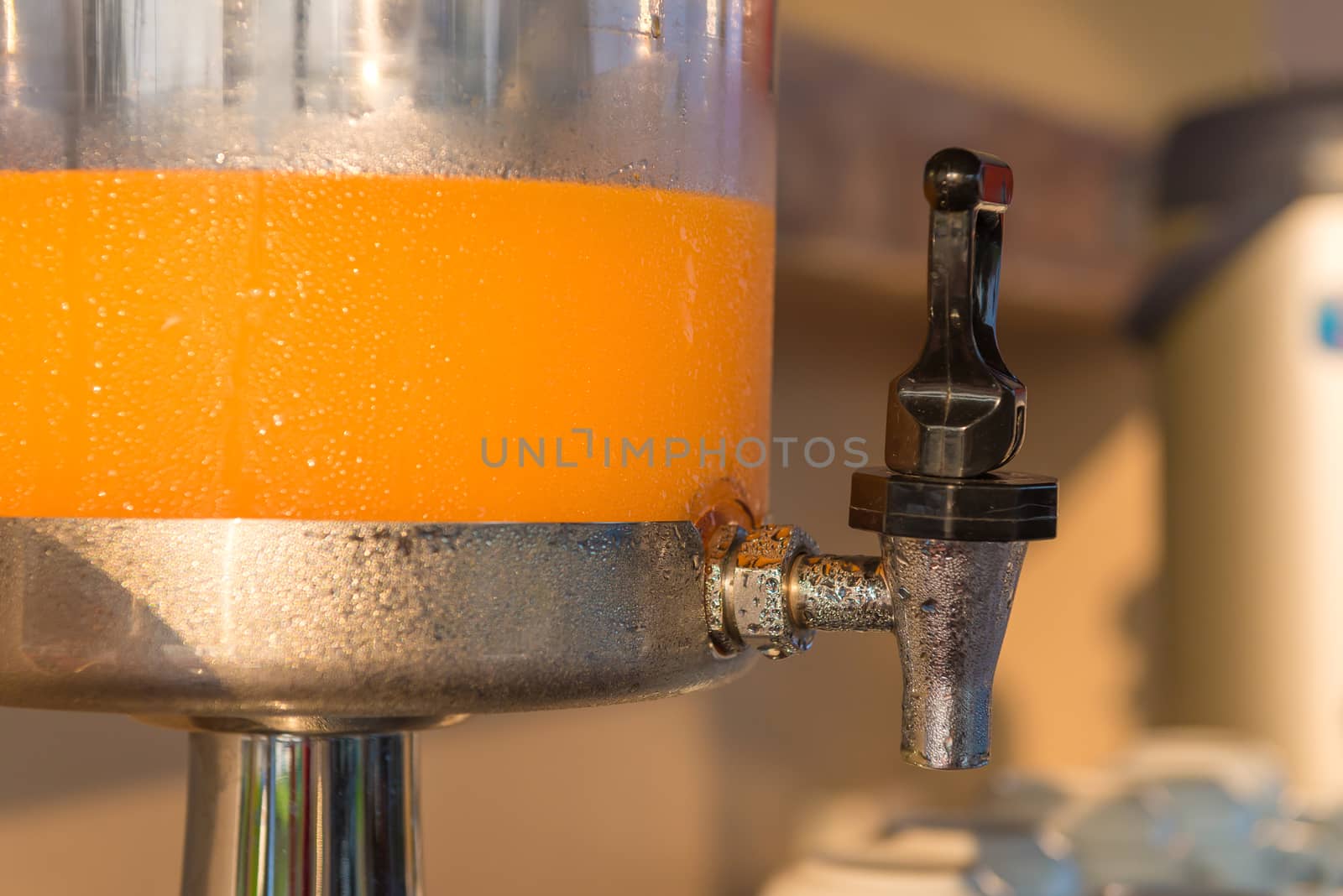 Orange juice in water cooler for breakfast at the hotel.