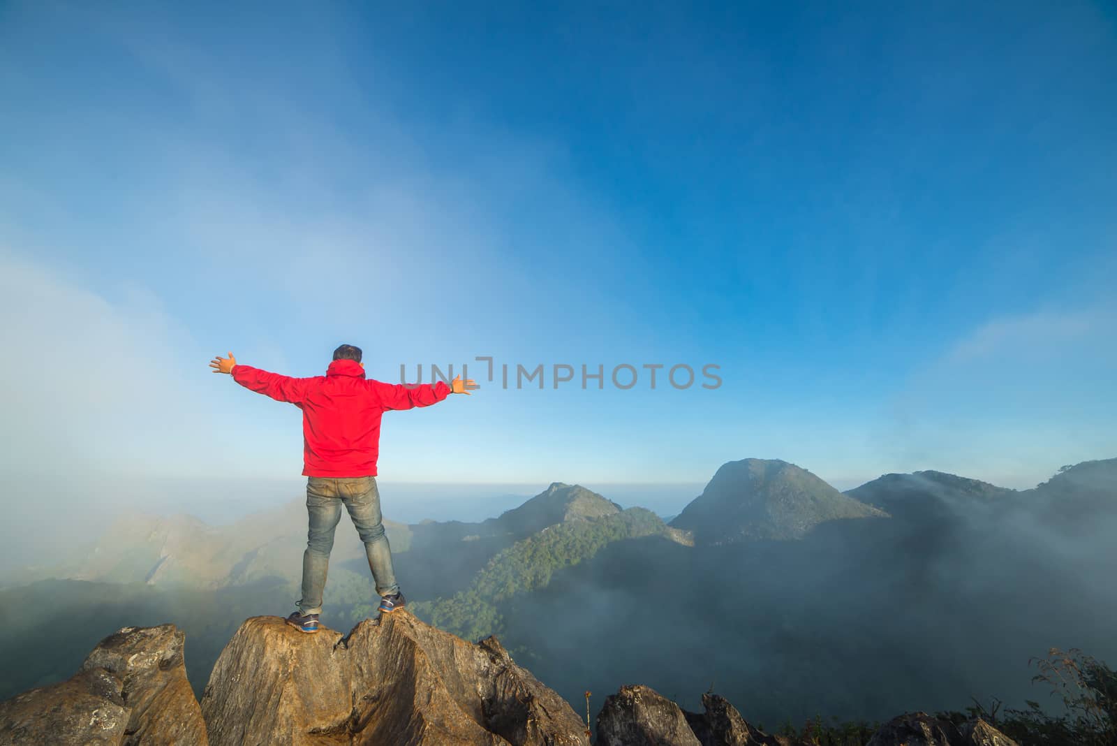 Man on top of mountain sitting on the rock watching a view landscape at Doi Luang Chiang Dao, ChiangMai Thailand.