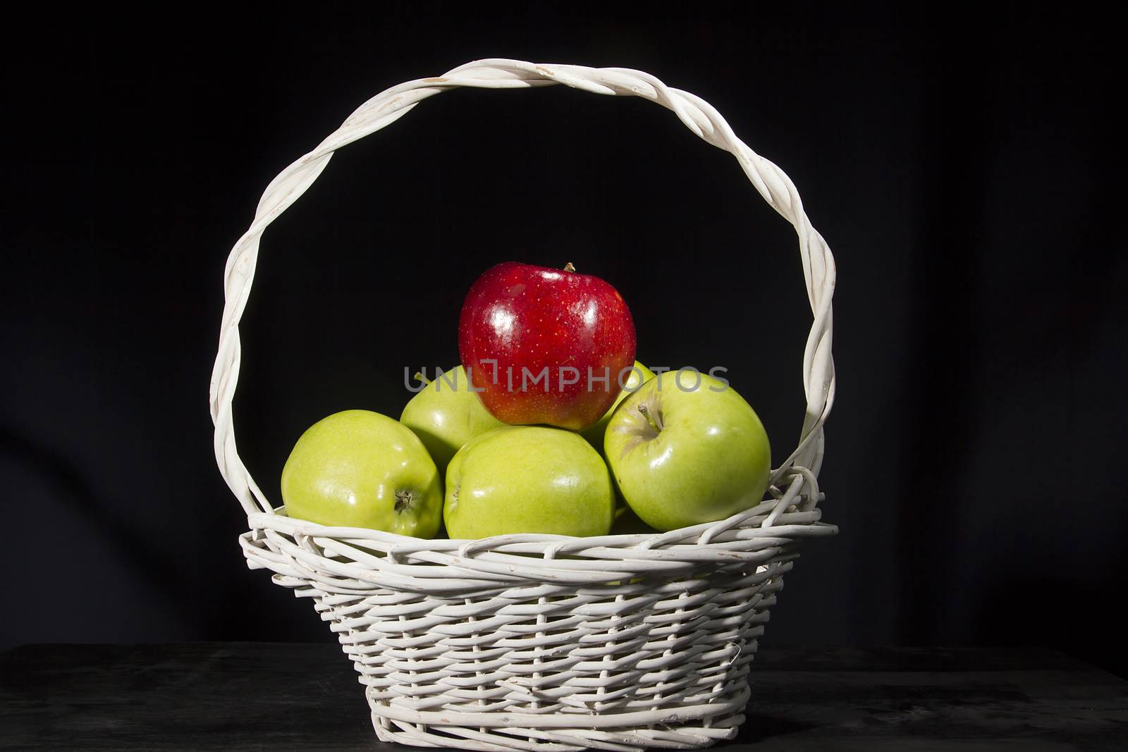 Ripe apples in a wicker basket on a black background
