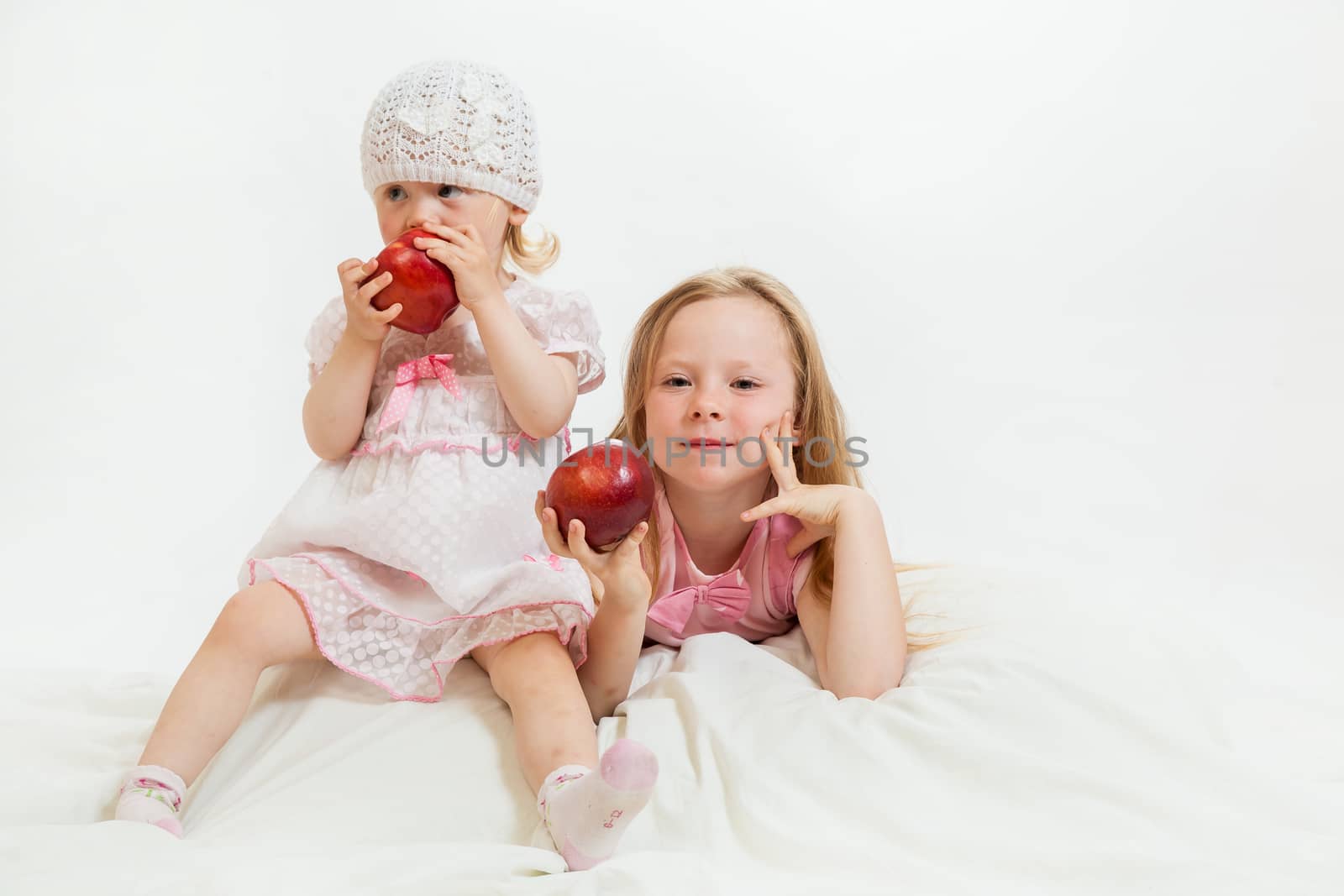 two little girls sit on the isolated background