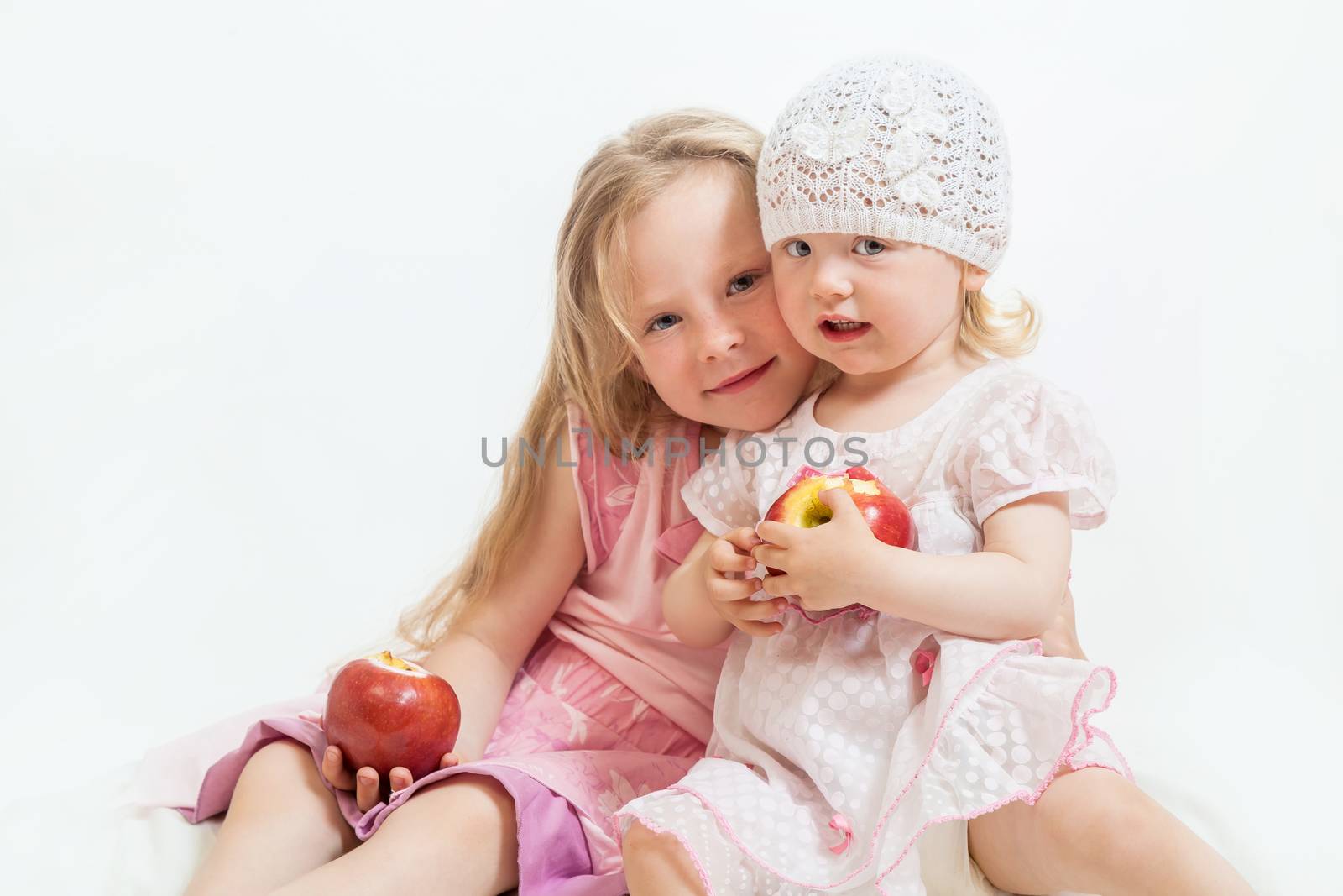 two little girls sit on the isolated background