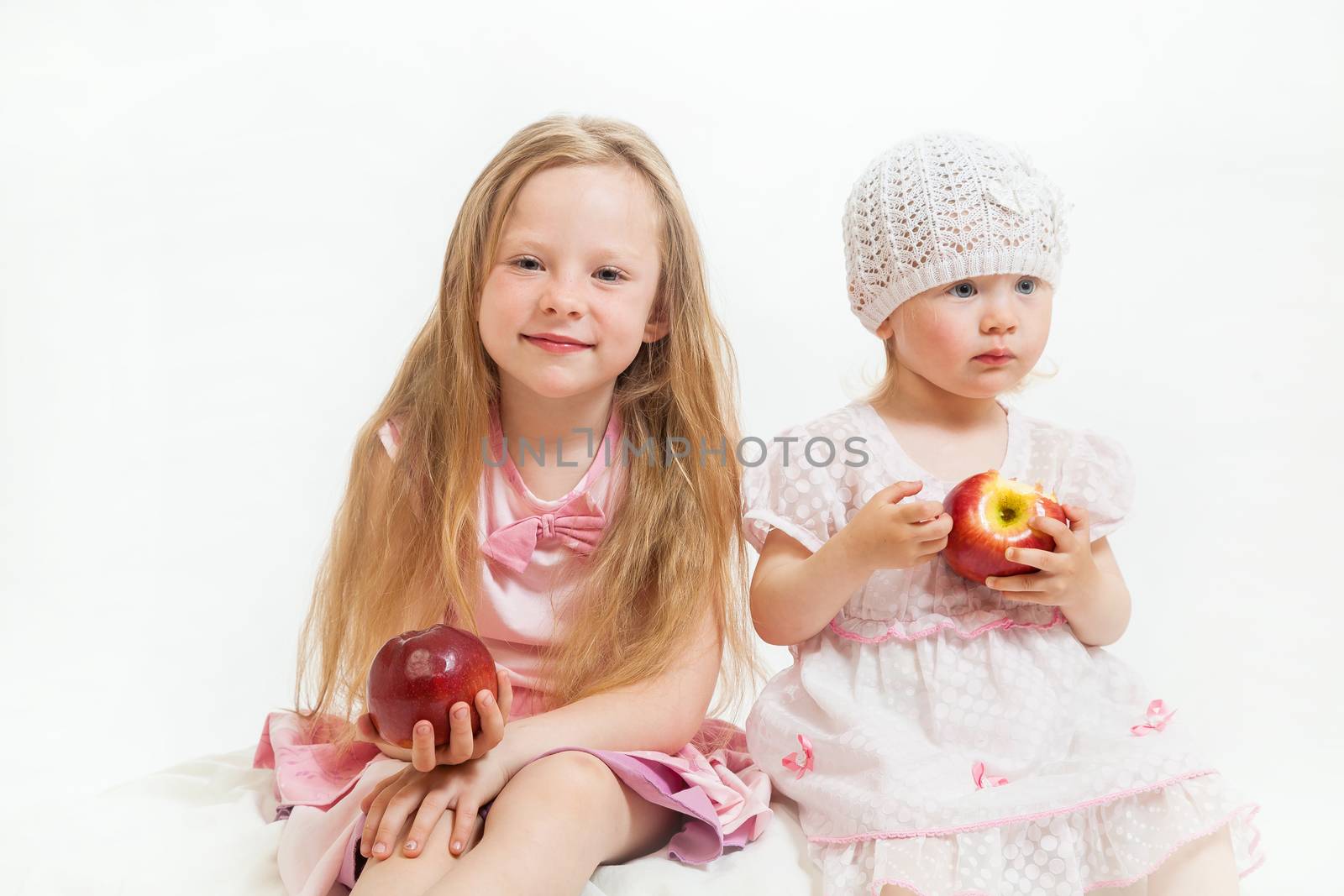 two little girls sit on the isolated background