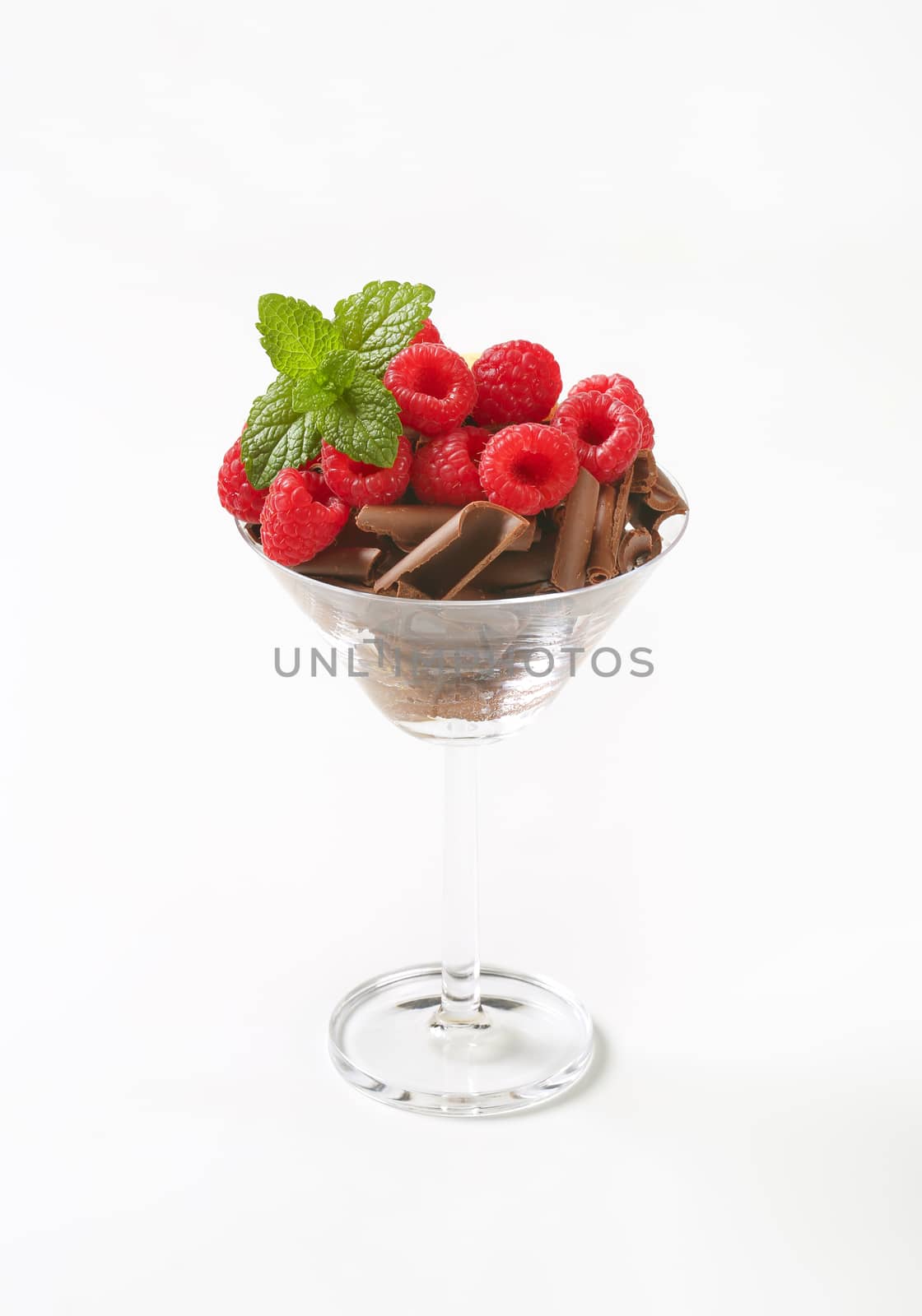Chocolate curls with fresh raspberries in stemmed glass
