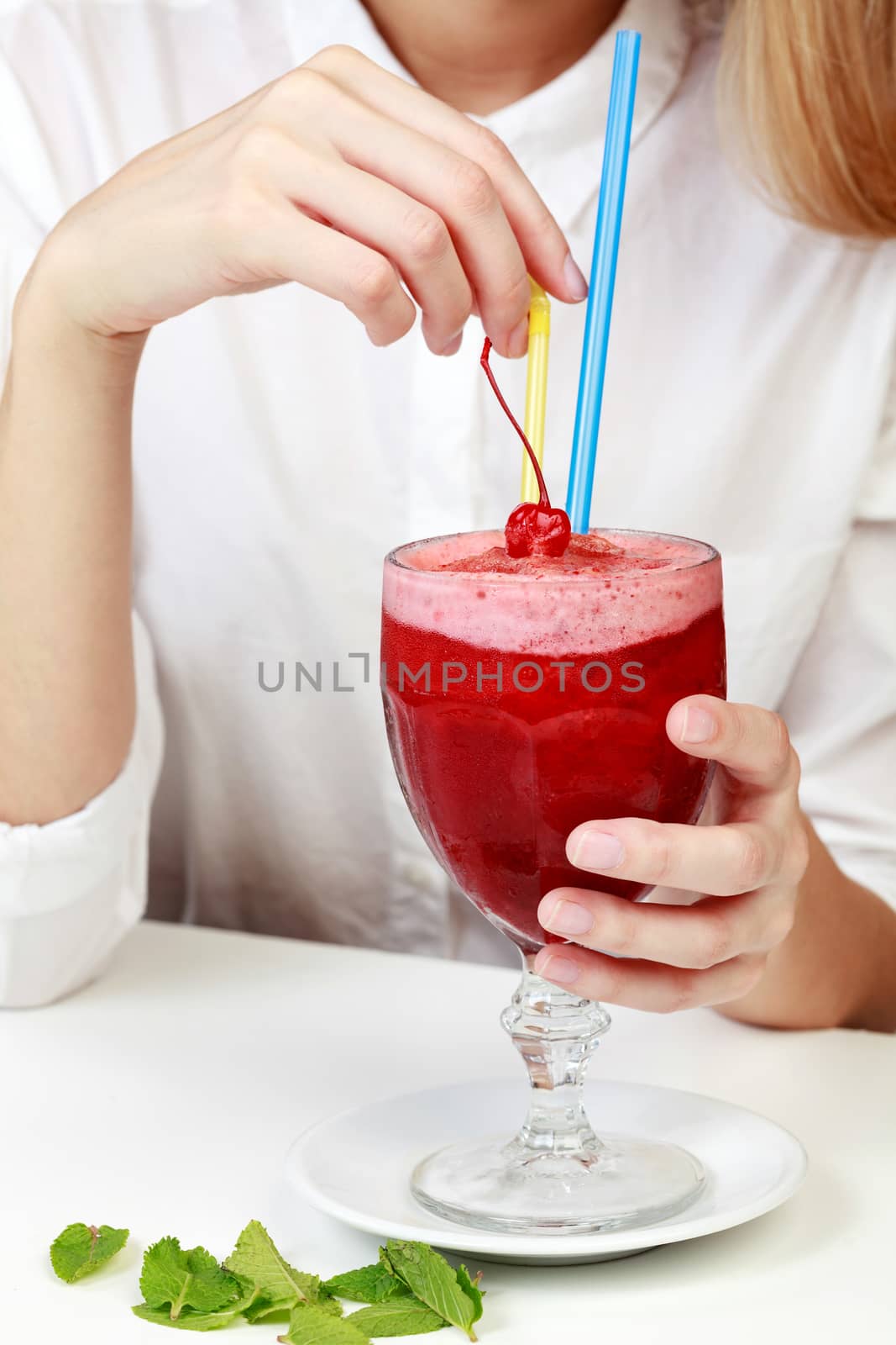 Cherry smoothie in a big glass cup with two straws in woman's ha by Nobilior