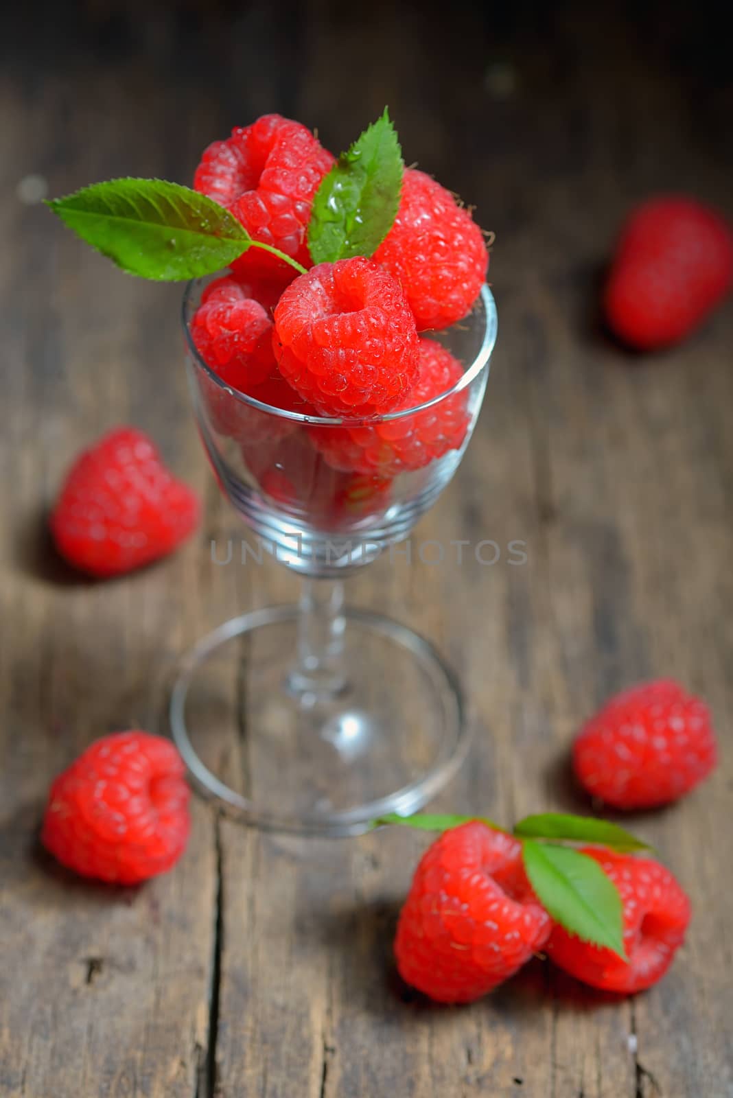 Raspberries in small glass on wooden table