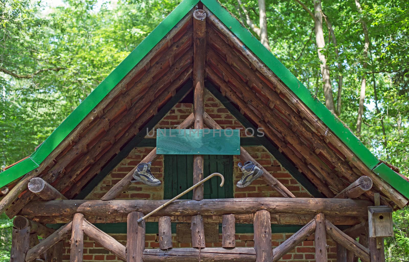 A wooden cabin with walking boots and walking stick in a forest