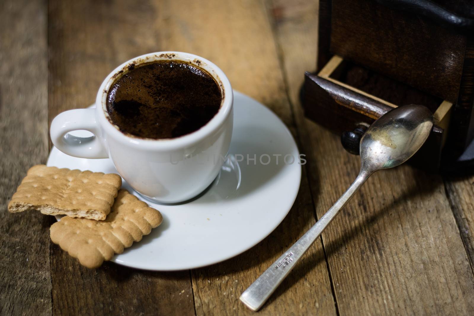 Freshly brewed coffee in mugs on a wooden table with a mill on a black background